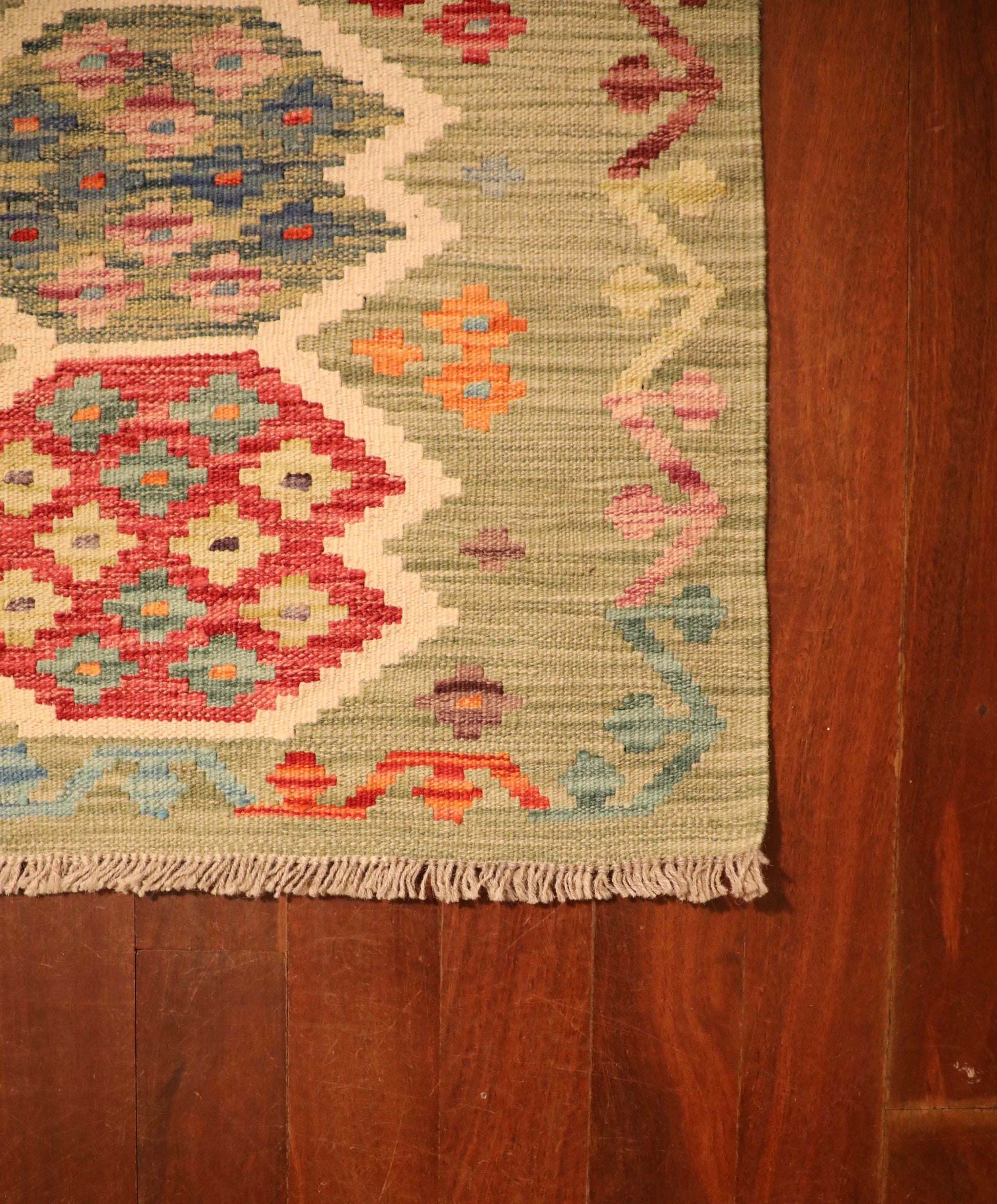 The Afghan Hand Woven Khyber Kilim - 65 X 92. Crafted using traditional vegetable dyed wool, and featuring traditional geometric designs. Colours, light greens, light blues, reds, beiges, creams, oranges and yellows. Size 65 X 92. Corner.