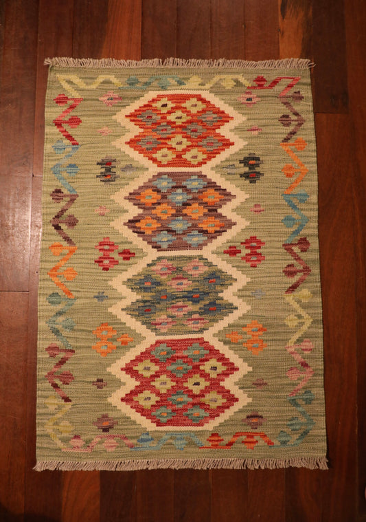 The Afghan Hand Woven Khyber Kilim - 65 X 92. Crafted using traditional vegetable dyed wool, and featuring traditional geometric designs. Colours, light greens, light blues, reds, beiges, creams, oranges and yellows. Size 65 X 92. Top.