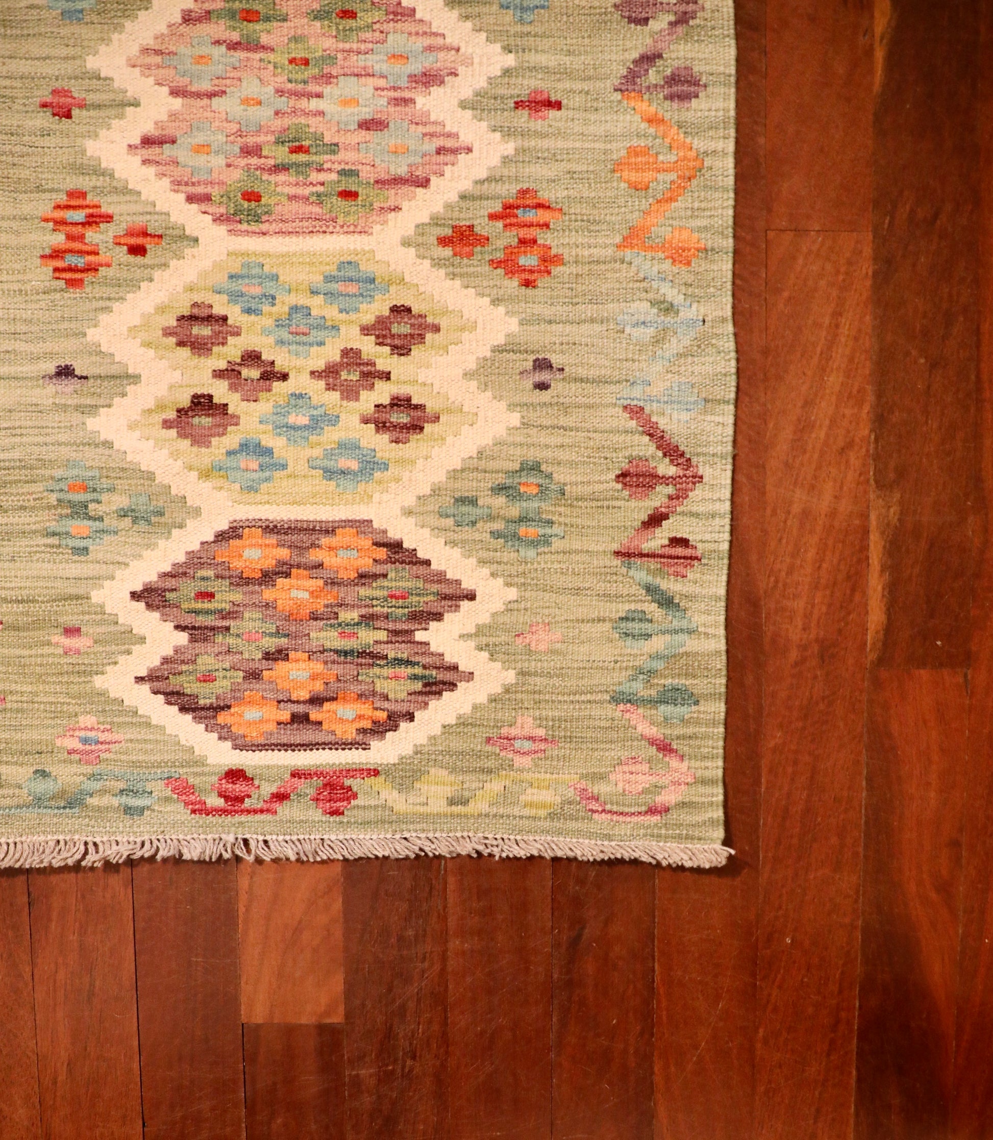 The Afghan Hand Woven Khyber Kilim - 67 X 94. Crafted using traditional vegetable dyed wool, and featuring traditional geometric designs. Colours, light greens, creams, light blues, reds and orange. Size 67 X 94. Corner.