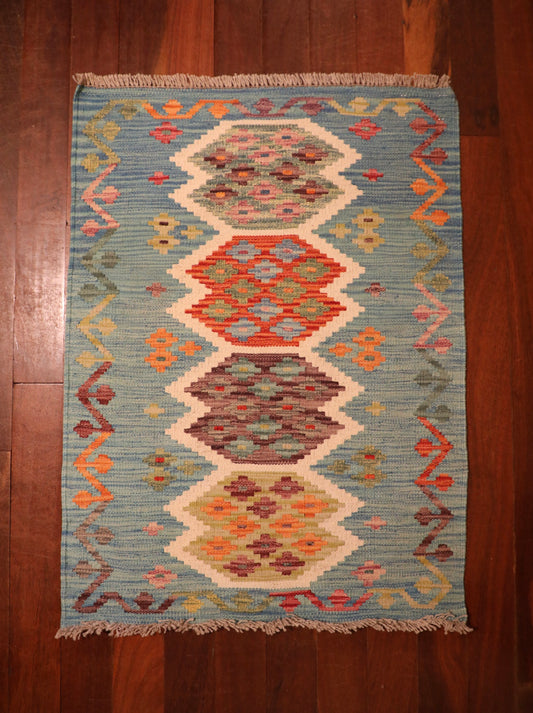 The Afghan Hand Woven Khyber Kilim - 68 X 92. Crafted using traditional vegetable dyed wool, and featuring traditional geometric designs. Colours, teal green, light blues, reds, beiges, creams, oranges and yellows. Size 68 X 92. Top.