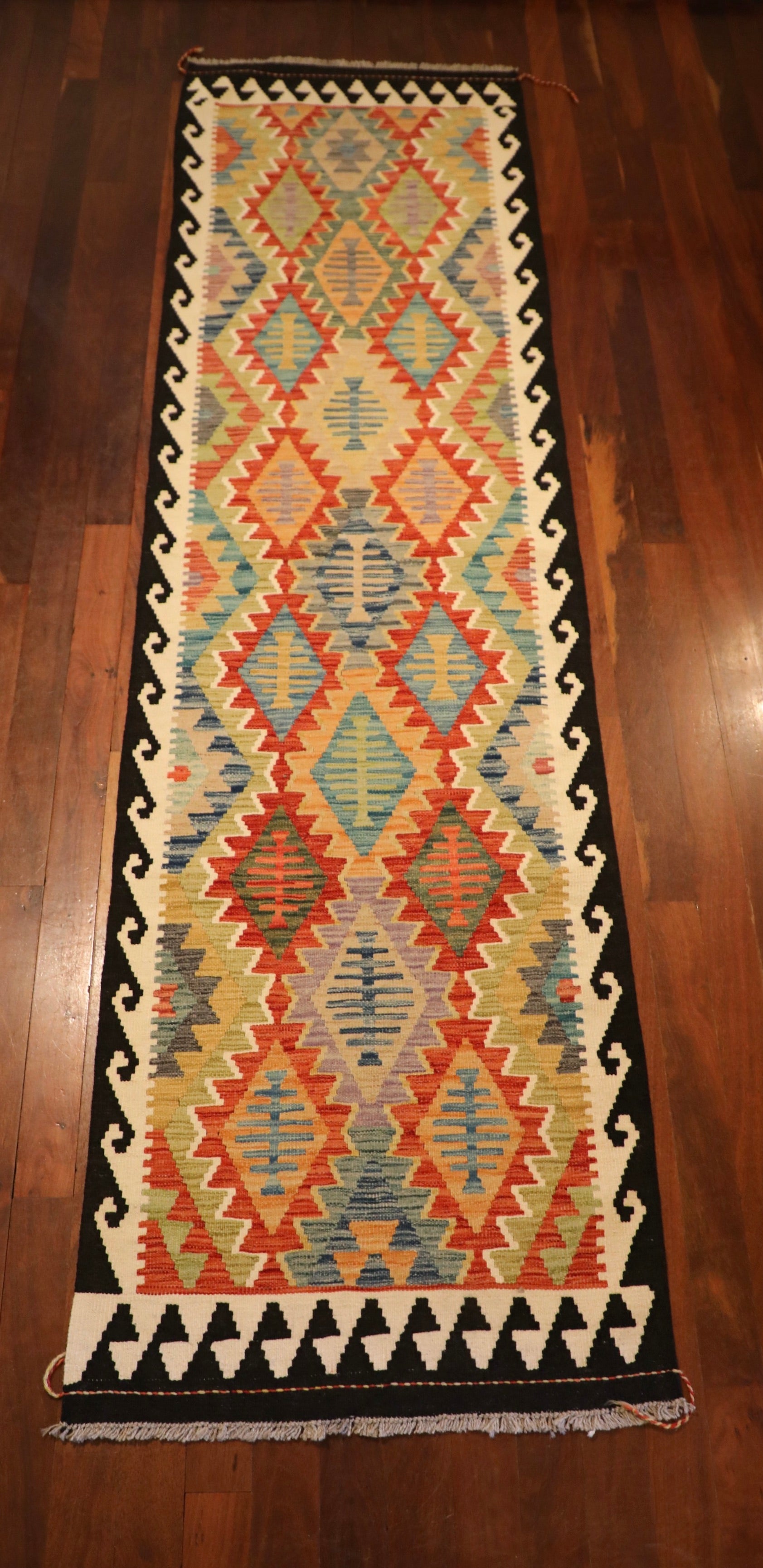The Afghan Hand Woven Khyber Kilim Runner - 79 X 293.  Crafted using traditional vegetable dyed wool, and featuring traditional geometric designs. Colours, dark blue, creams, beiges, oranges, light greens and more. Measures 79 wide X 293 long. Top.