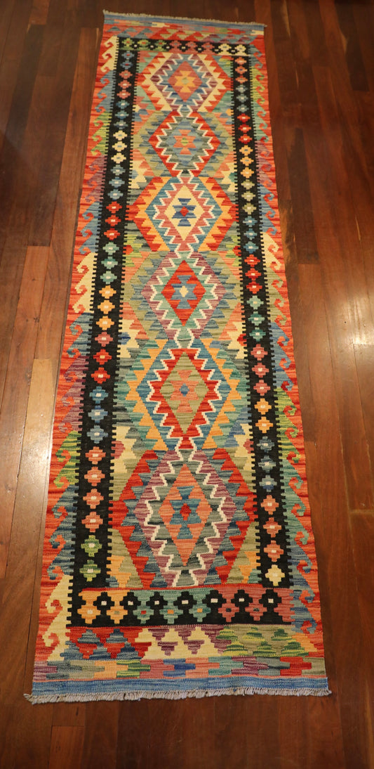 The Afghan Hand Woven Khyber Kilim Runner - 80 X 295.  Crafted using traditional vegetable dyed wool, and featuring traditional geometric designs. Colours, ,Oranges, blues, creams, reds, yellows, aqua and more. Measures 80 wide X 295 long. Top.