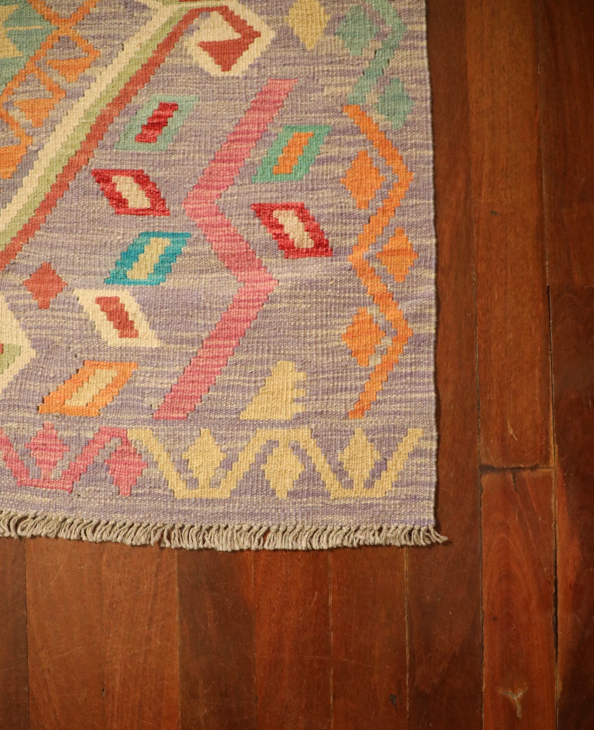 The Afghan Hand Woven Khyber Kilim - 127 X 174. Crafted using traditional vegetable dyed wool, and featuring traditional geometric designs. Colours, lavenders, beiges, creams, oranges. Size 127 X 174. Corner.