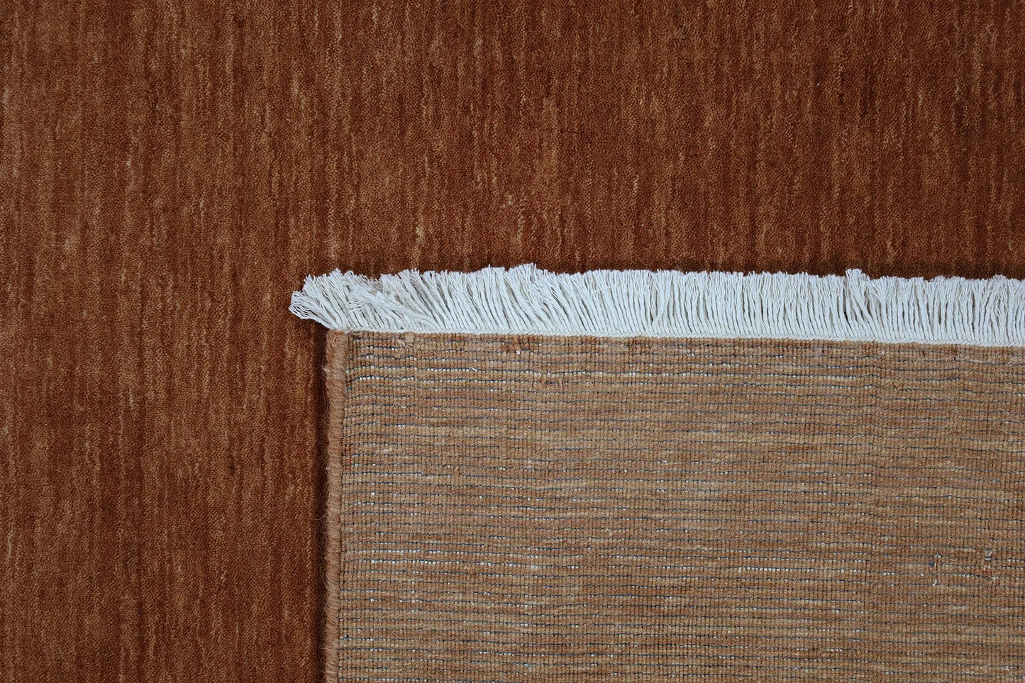 Lori Brick is a luxurious hand loomed floor rug made of 100% wool. The wool material creates a soft texture and a smooth pile height of 16-18mm. Colour orangish/redish terracotta with cream tassels. Sizes 160 X 230, 200 X 290, 240 X 340 and 300 X 400. Fold.