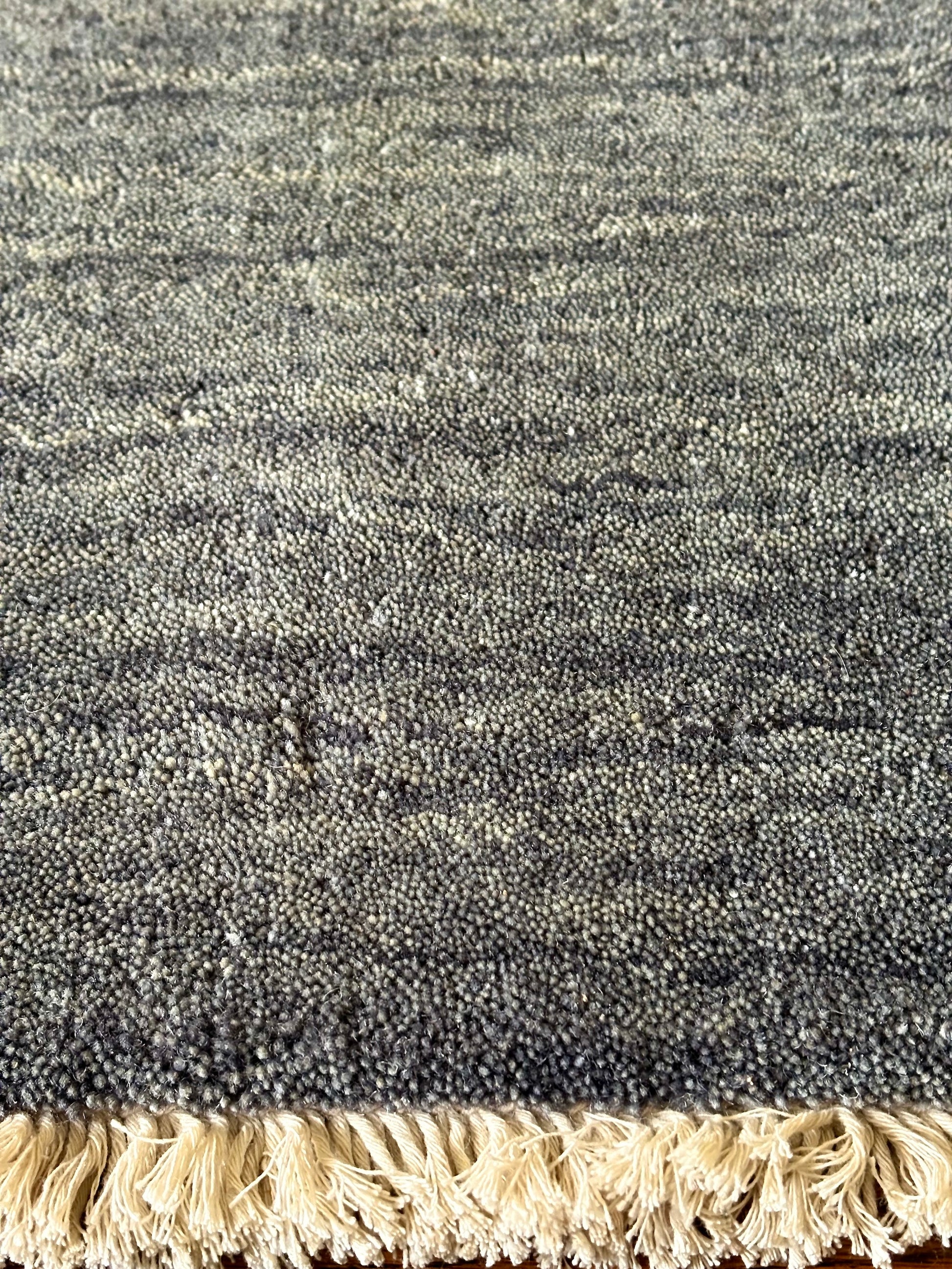 Lori Smoke is a luxurious hand loomed floor rug made of 100% wool. The wool material creates a soft texture and a smooth pile height of 16-18mm. Colour dark smokey Grey with cream tassels. Sizes 160 X 230, 200 X 290, 240 X 340 and 300 X 400. Close Edge.