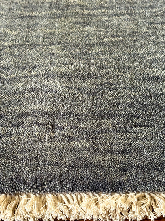 Lori Smoke is a luxurious hand loomed floor rug made of 100% wool. The wool material creates a soft texture and a smooth pile height of 16-18mm. Colour dark smokey Grey with cream tassels. Sizes 160 X 230, 200 X 290, 240 X 340 and 300 X 400. Close Edge.