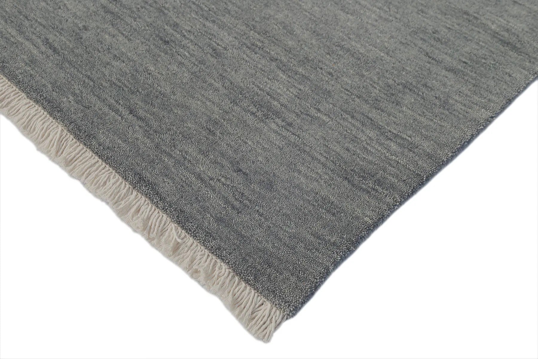 Lori Smoke is a luxurious hand loomed floor rug made of 100% wool. The wool material creates a soft texture and a smooth pile height of 16-18mm. Colour dark smokey Grey with cream tassels. Sizes 160 X 230, 200 X 290, 240 X 340 and 300 X 400. Corner.