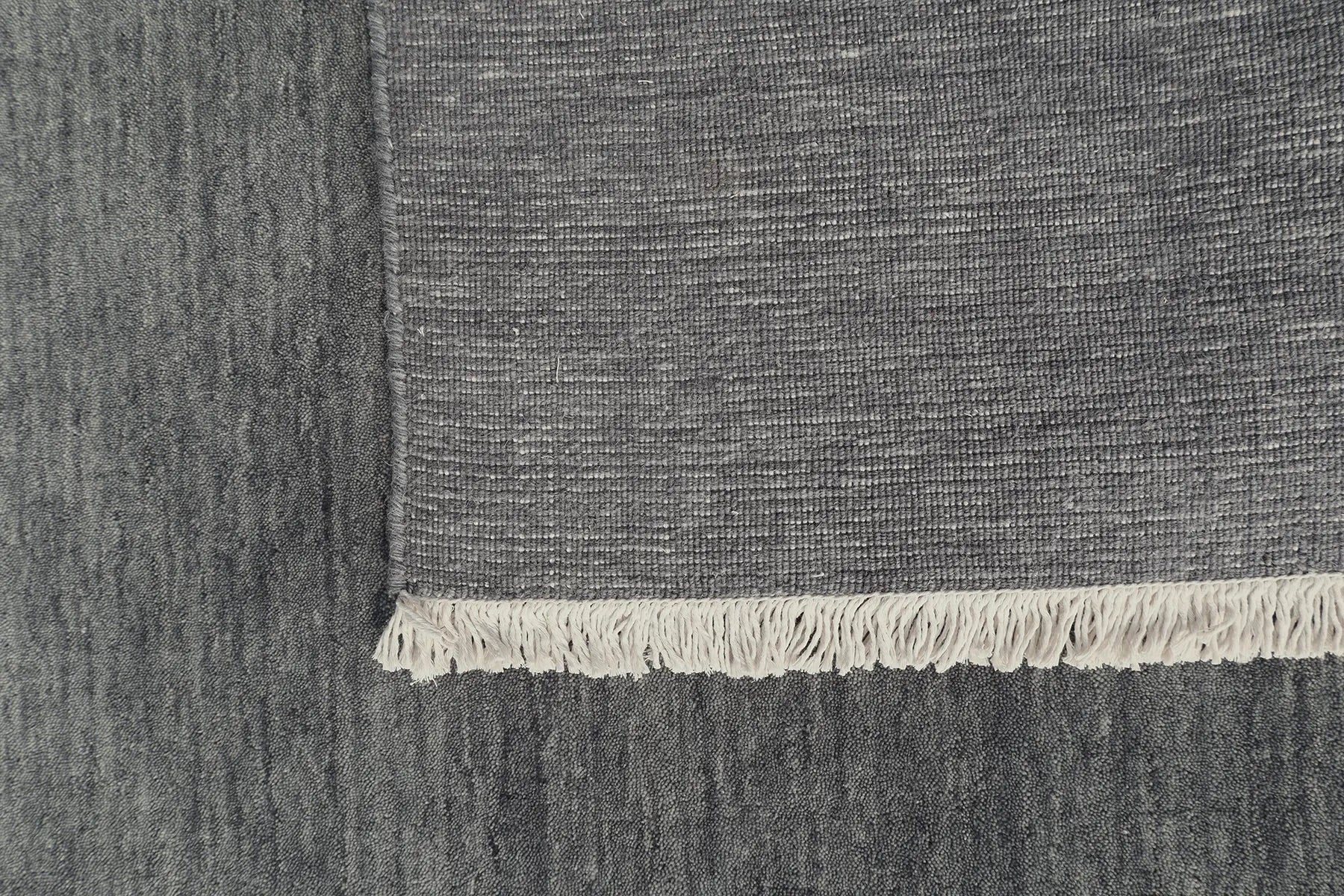 Lori Smoke is a luxurious hand loomed floor rug made of 100% wool. The wool material creates a soft texture and a smooth pile height of 16-18mm. Colour dark smokey Grey with cream tassels. Sizes 160 X 230, 200 X 290, 240 X 340 and 300 X 400. Fold.