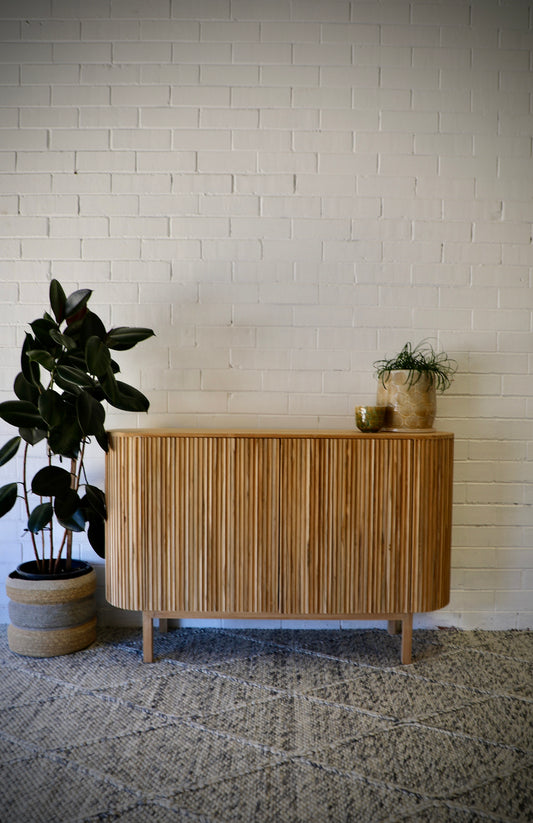 The Medford 2 Door Buffet. Crafted from solid teak, with rounded sides and sits on sleek legs. Colour Natural. Measures 1250L X 350D X 800H. Front Styled.