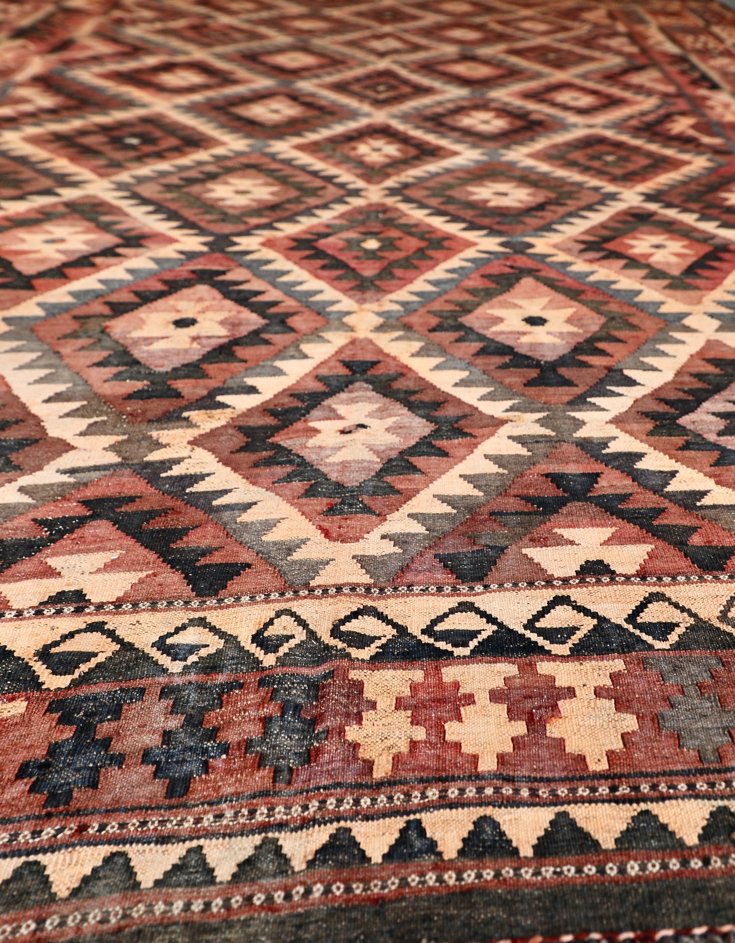 The Afghan Hand Woven Maimana Kilim - 251 X 344.  Crafted from wool and featuring traditional Afghan weaving techniques. Colours, red, orange, black. Size 251 wide X 344 long. Angle.