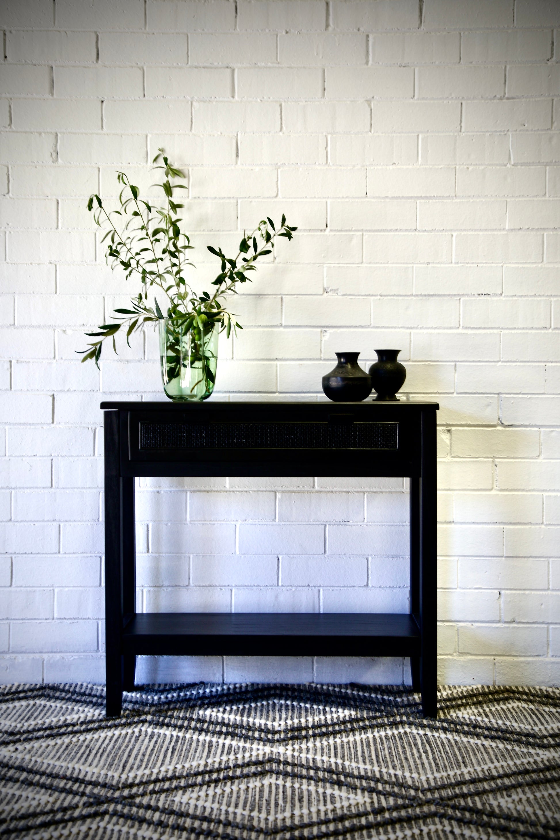 The Milan - 1 Drawer Black console boasts coastal and contemporary style. Crafted from sustainable white cedar timber, it features 1 drawer, on wooden runners, and an open mesh rattan drawer face. Colour Black. Measures 800 length X 250 depth X 750 height. Front Styled.