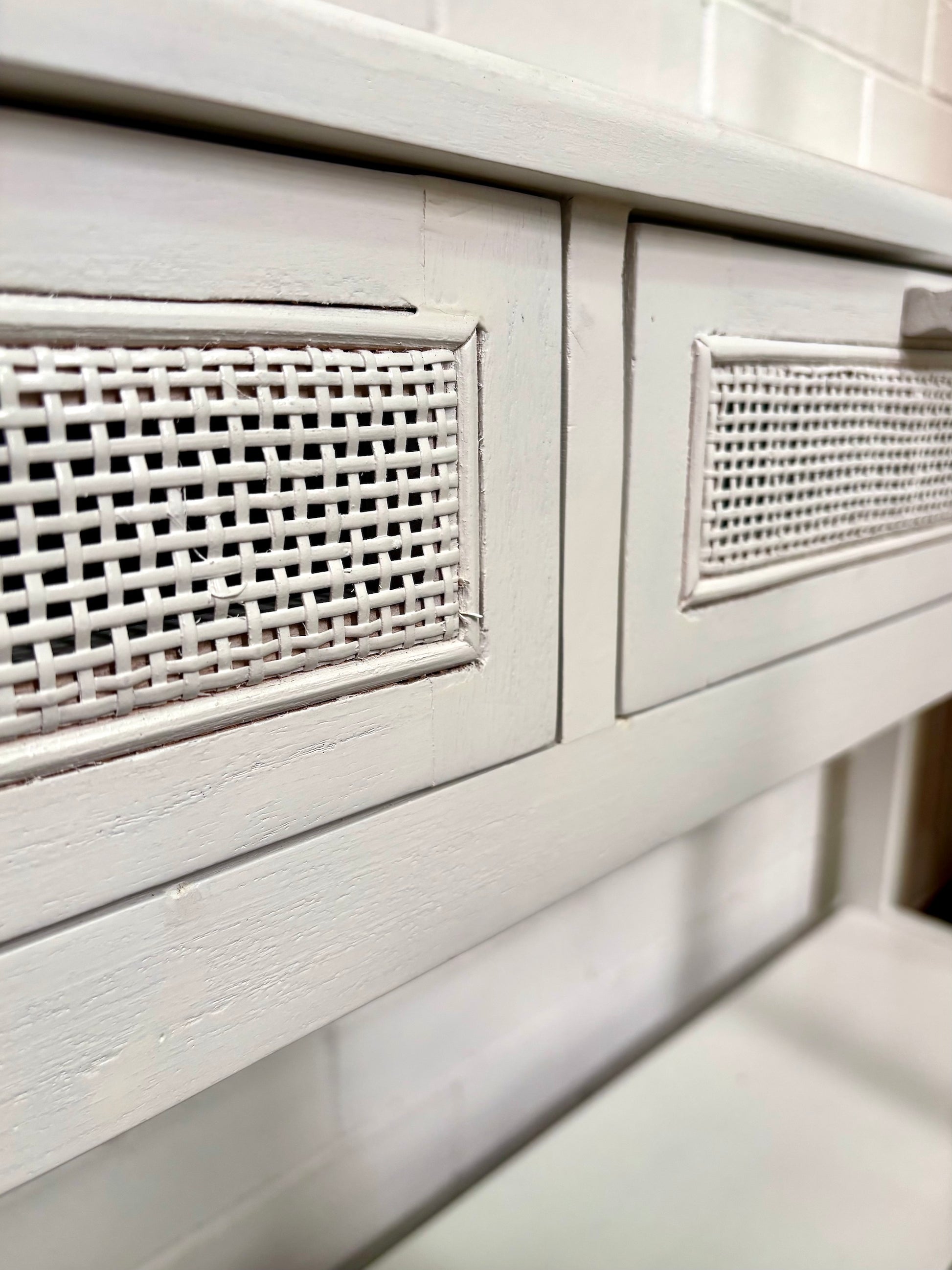 The Milan - 2 Drawer White console boasts coastal and contemporary style. Crafted from sustainable white cedar timber, it features 2 drawers, on wooden runners, and an open mesh rattan drawer face. Colour White. Measures 1500 length X 250 depth X 750 height. Angle Close.