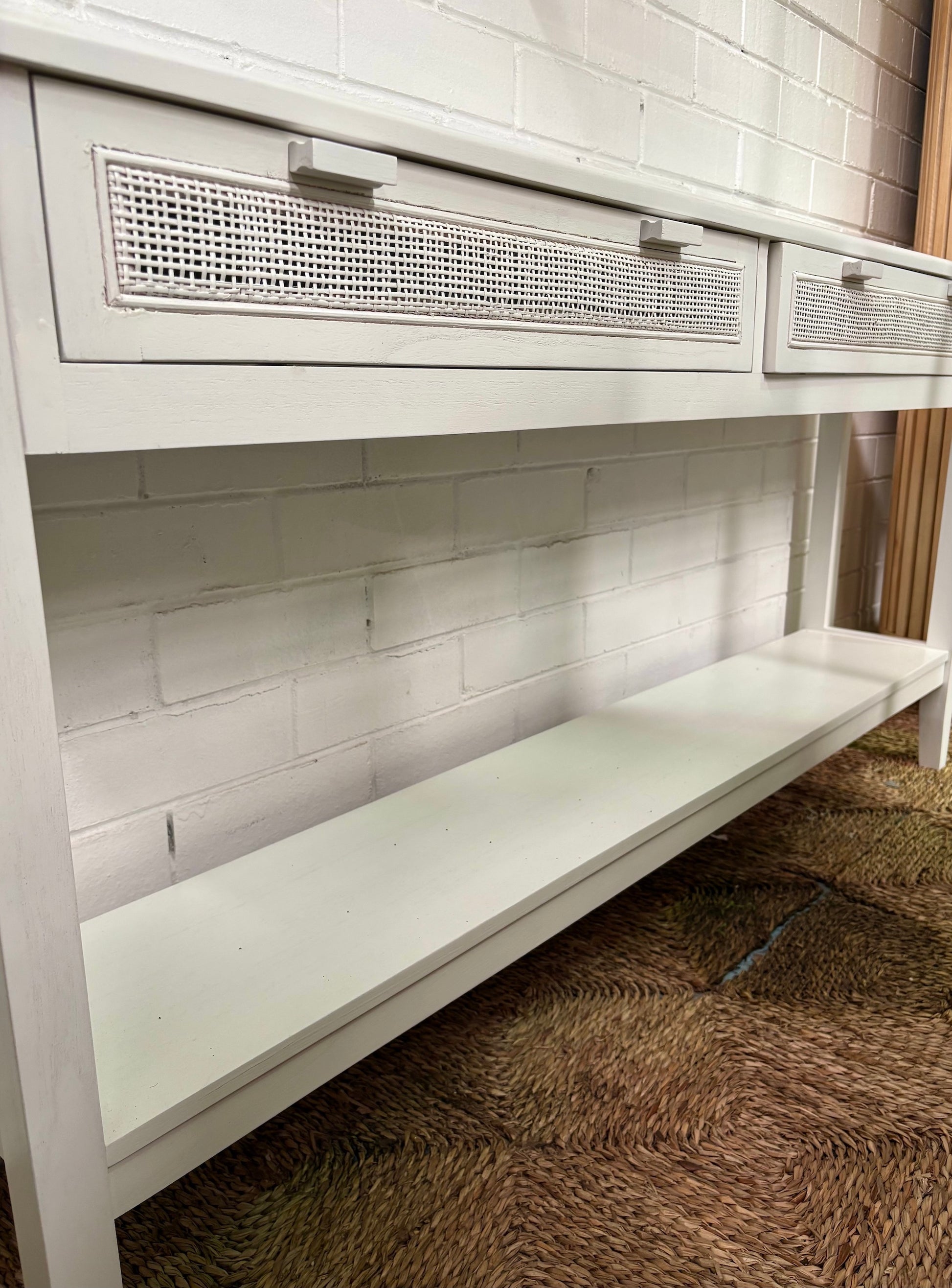 The Milan - 2 Drawer White console boasts coastal and contemporary style. Crafted from sustainable white cedar timber, it features 2 drawers, on wooden runners, and an open mesh rattan drawer face. Colour White. Measures 1500 length X 250 depth X 750 height. Full Angle.