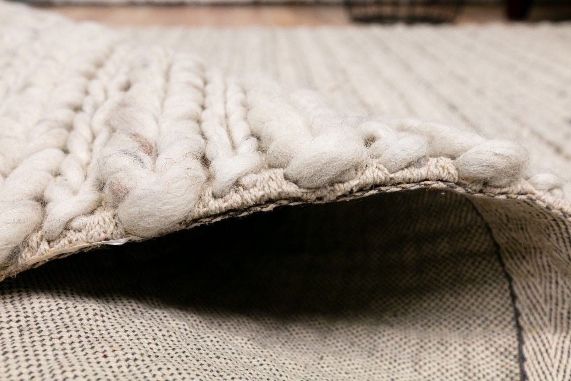 Oslo Braided is a textured hand woven,  braided piled wool rug. Colours white with grey,  black and brown accents. Sizes 155 X 225, 200 X 290, 240 X 320 and 300 X 400. Side.