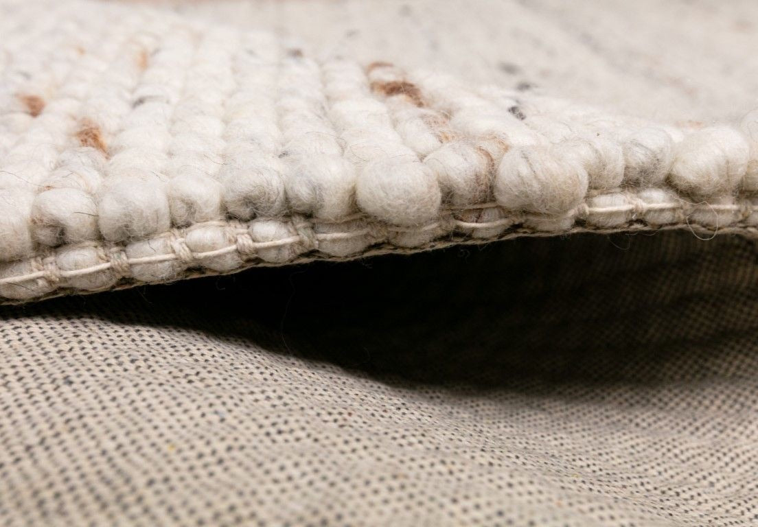 Oslo Bubble is a textured hand woven,  looped piled wool rug. Colours white with grey,  black and brown accents. Sizes 155 X 225, 200 X 290, 240 X 320 and 300 X 400. Side.