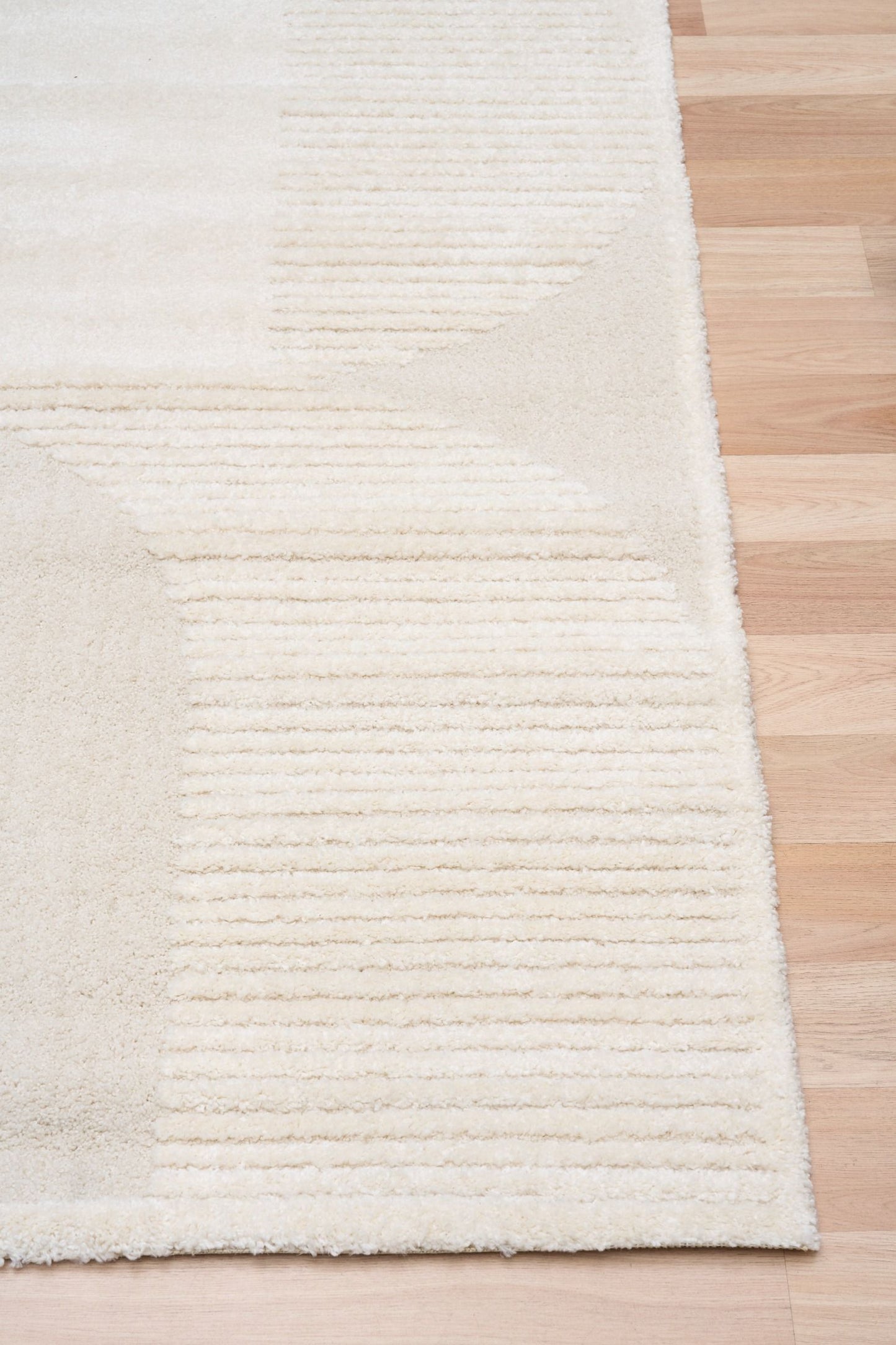 Osmond Waves Ivory rug with soft geometric patterns in a neutral palette and a high-low textured finish. Colours Ivory and Light Grey. Sizes 160 X 230, 200 X 290 and 240 X 340. Corner.