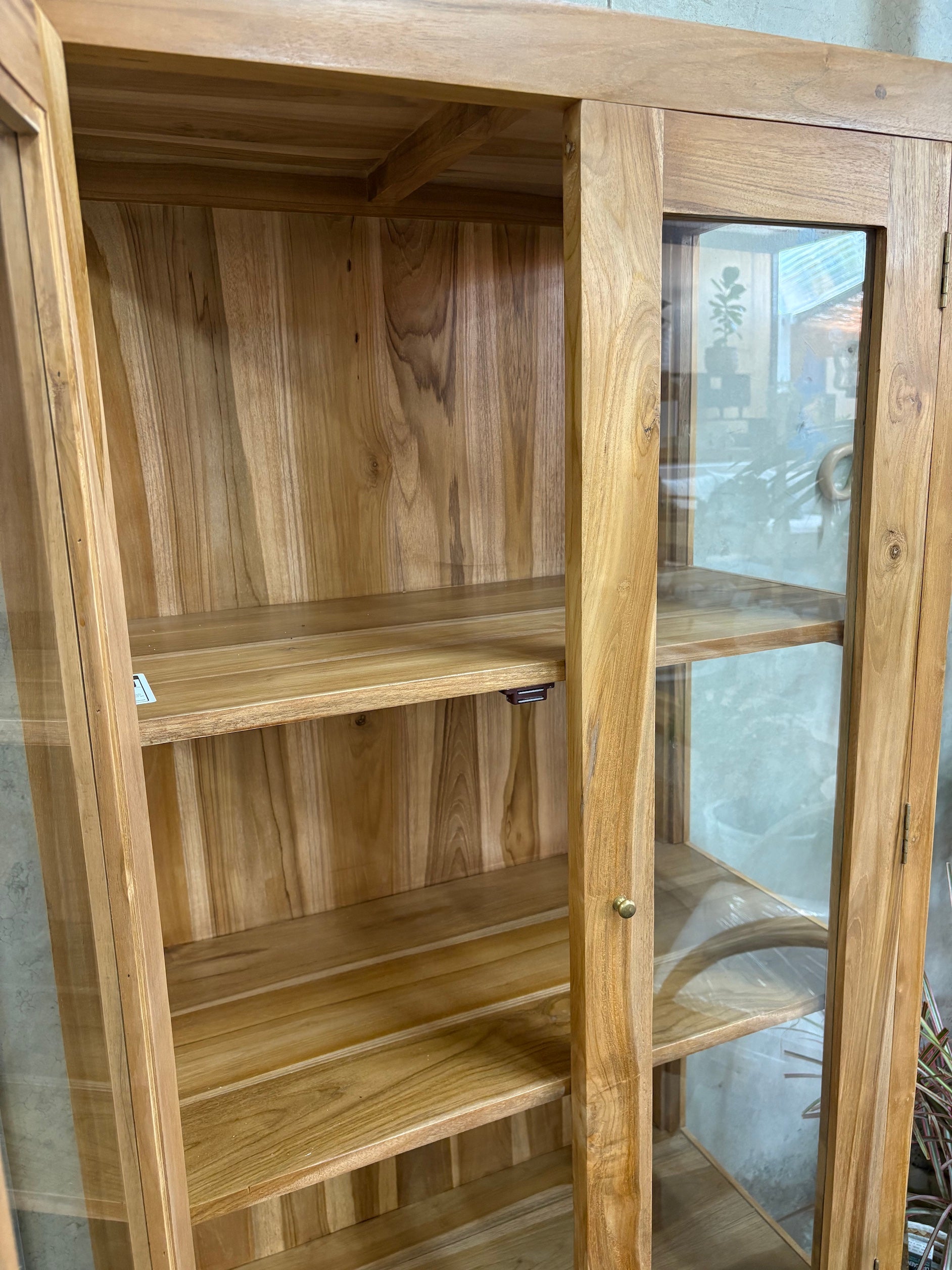 The Pisces Cabinet. Crafted from A grade teak featuring 2 glass doors and 1 lower shelf. Colour Natural. Measures 1700H x 450D x 800W. Angle Open.