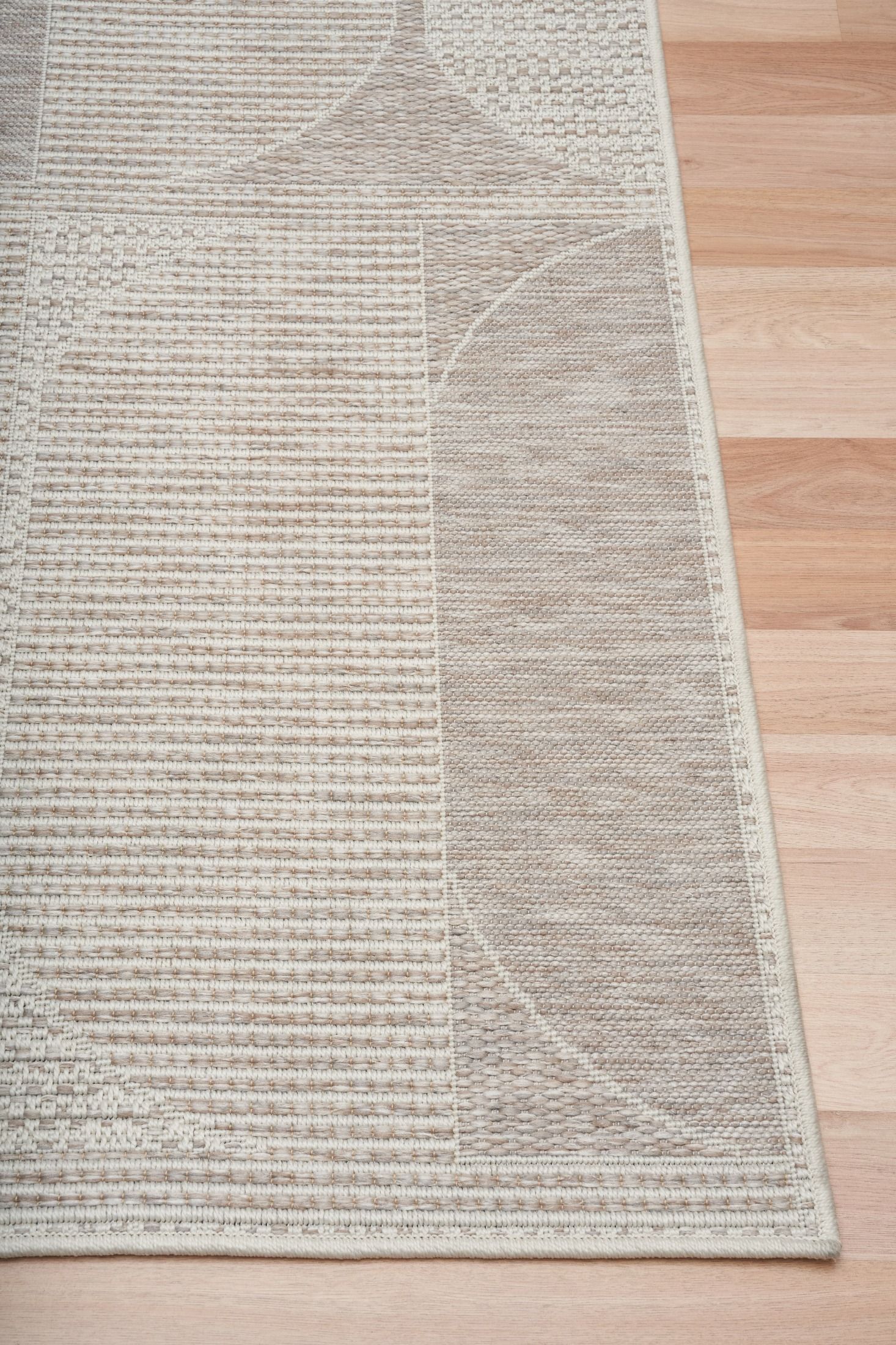 The Patio Linen 65001 indoor/outdoor rug featuring neutral tones and a modern designed pattern, power-loomed from UV-stabilised polypropylene for lasting durability. Colours, Linen, Beiges and hints of light grey. 3 sizes. Corner.