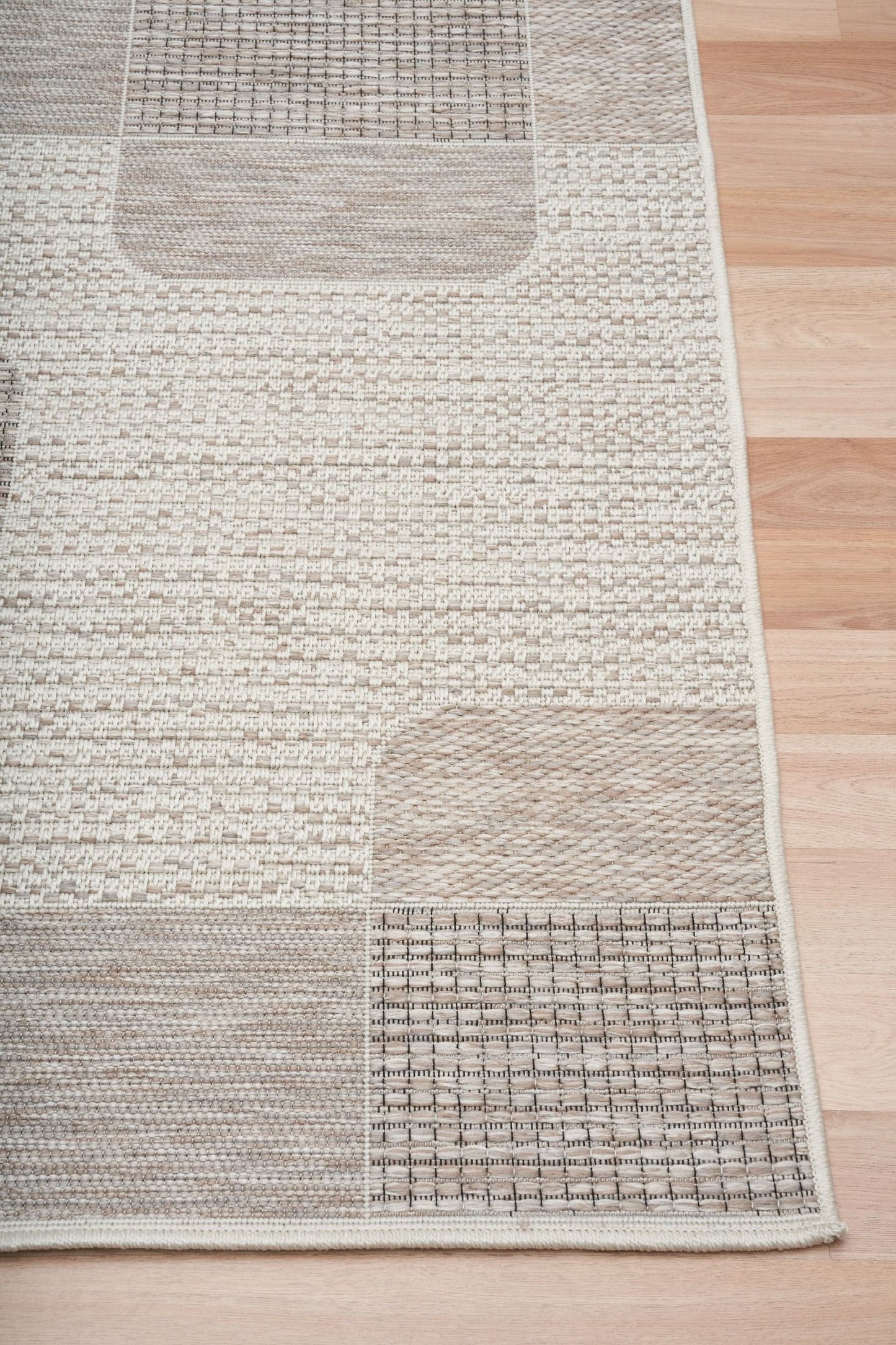 The Patio Squares Linen indoor/outdoor rug featuring neutral tones and a modern designed pattern, power-loomed from UV-stabilised polypropylene for lasting durability. Colours, Linen, Beiges and hints of light grey. 3 sizes. Corner.