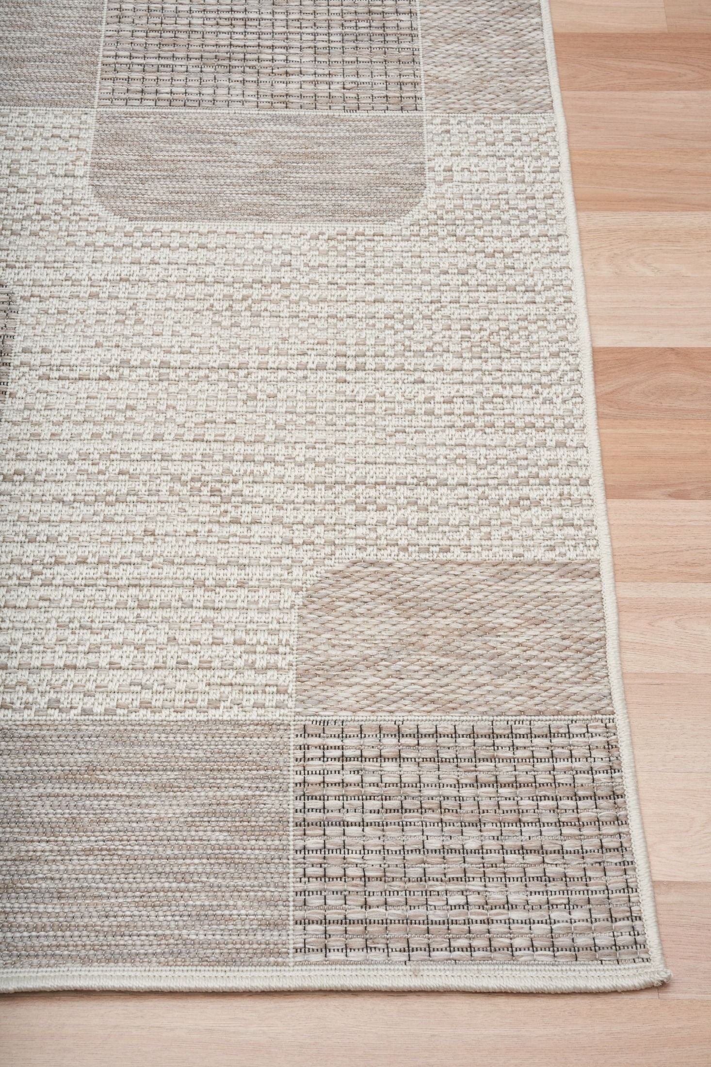 The Patio Squares Linen indoor/outdoor rug featuring neutral tones and a modern designed pattern, power-loomed from UV-stabilised polypropylene for lasting durability. Colours, Linen, Beiges and hints of light grey. 3 sizes. Corner.