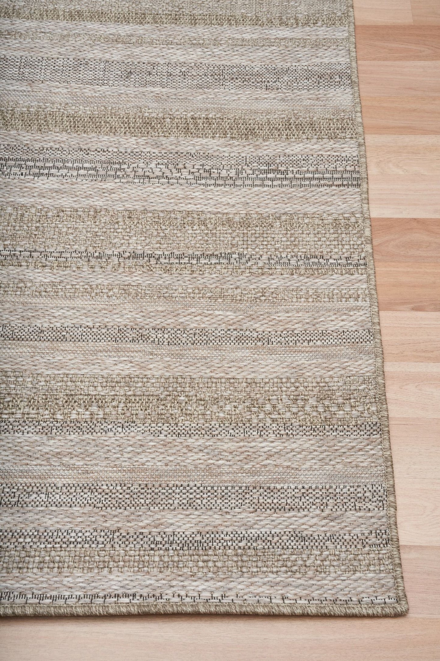 The Patio Straw 900 indoor/outdoor rug featuring neutral tones and a subtle textured pattern, power-loomed from UV-stabilised polypropylene for lasting durability. Colour Browns, Beiges and hints of black. 3 sizes. Corner.