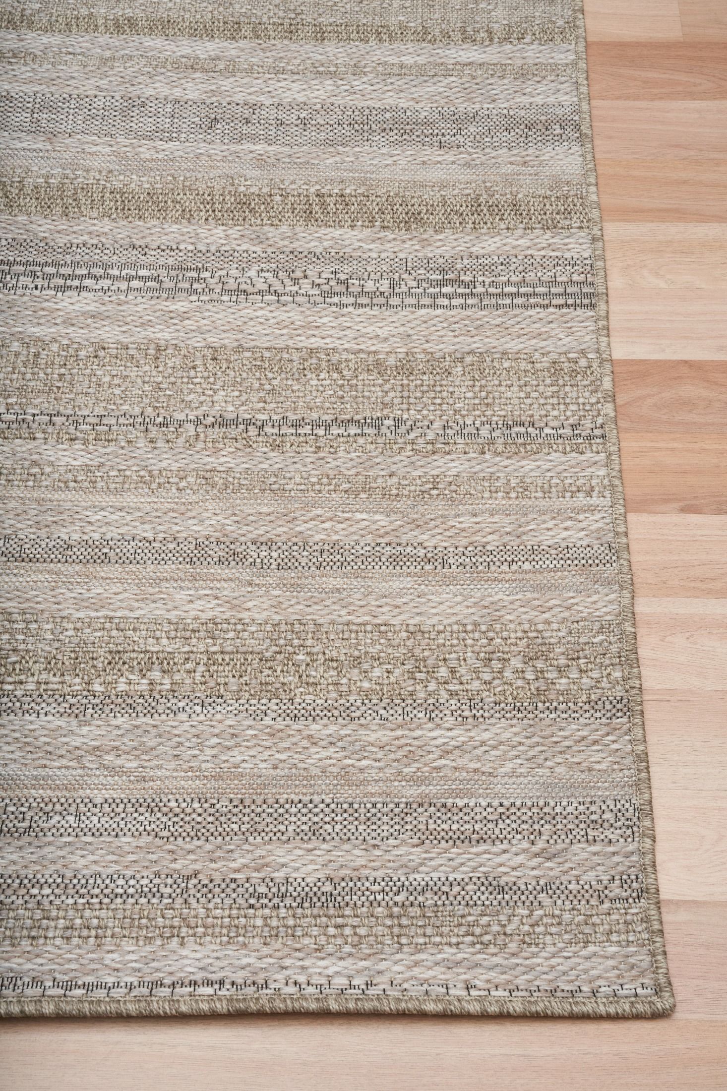 The Patio Straw 900 indoor/outdoor rug featuring neutral tones and a subtle textured pattern, power-loomed from UV-stabilised polypropylene for lasting durability. Colour Browns, Beiges and hints of black. 3 sizes. Corner.