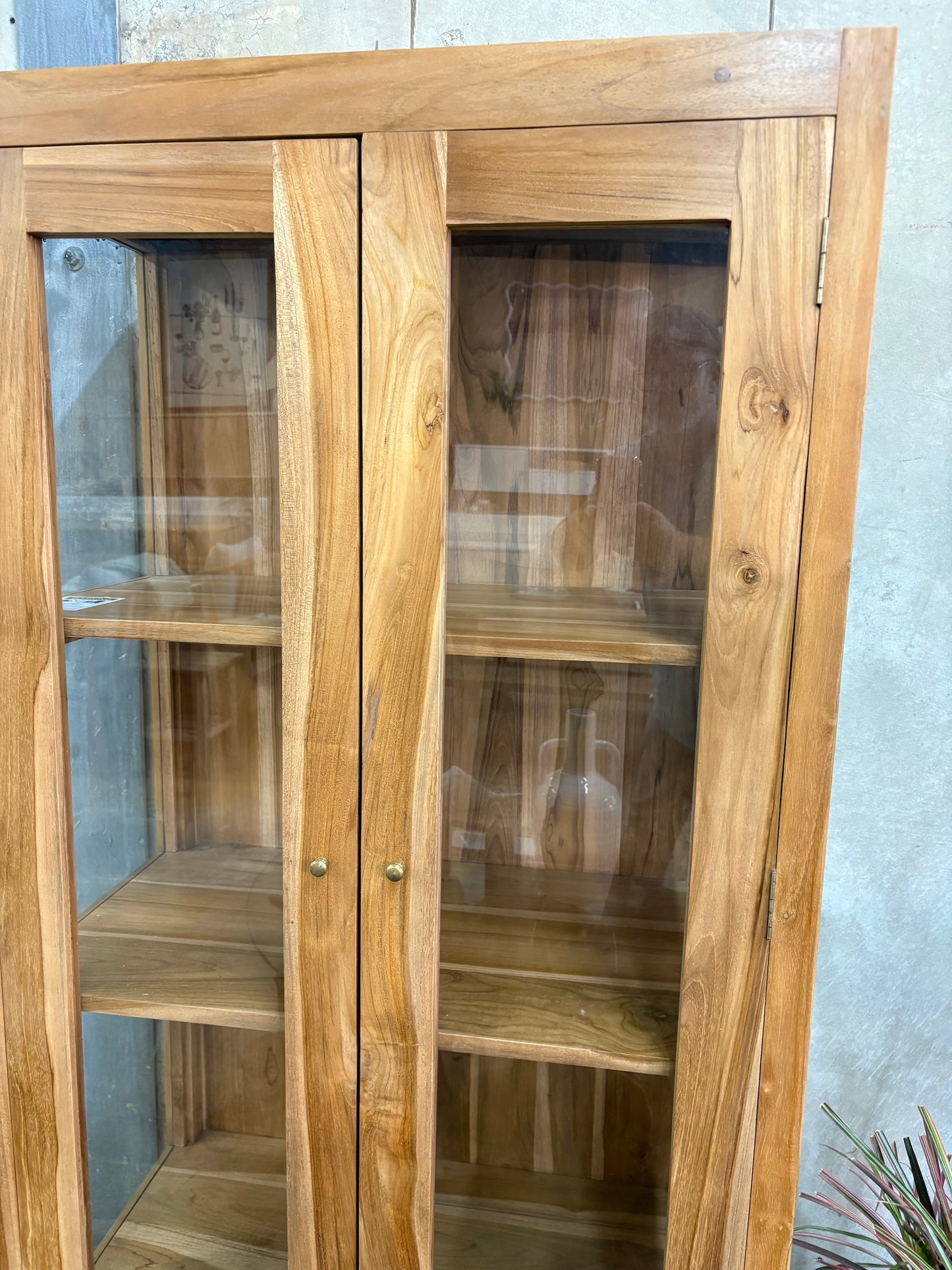 The Pisces Cabinet. Crafted from A grade teak featuring 2 glass doors and 1 lower shelf. Colour Natural. Measures 1700H x 450D x 800W. Front Angle.