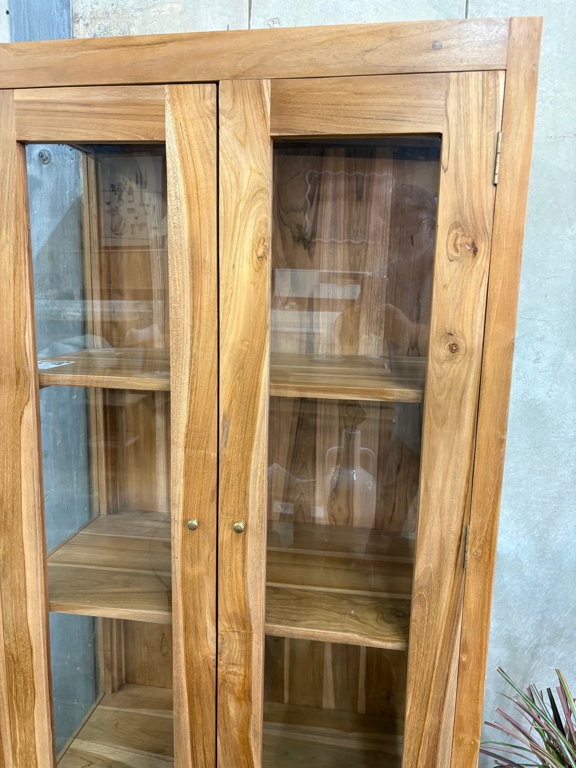 The Pisces Cabinet. Crafted from A grade teak featuring 2 glass doors and 1 lower shelf. Colour Natural. Measures 1700H x 450D x 800W. Front Angle.