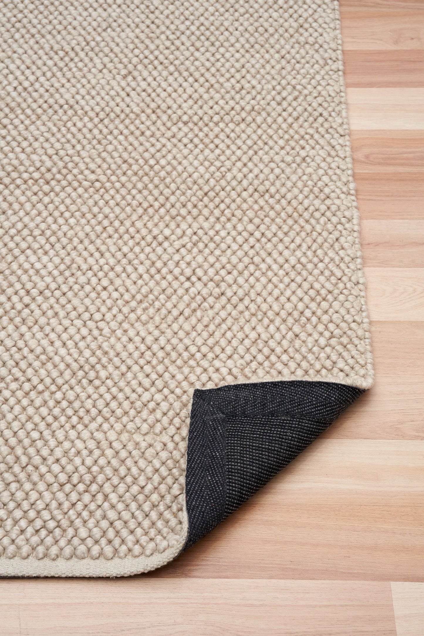 Rusta Beige hand-woven wool rug featuring a looped pile textured design in soft neutral beige tones, ideal for modern and contemporary interiors. Sizes 155 X 225, 200 X 290, 240 X 320 and 300 X 400. Fold.