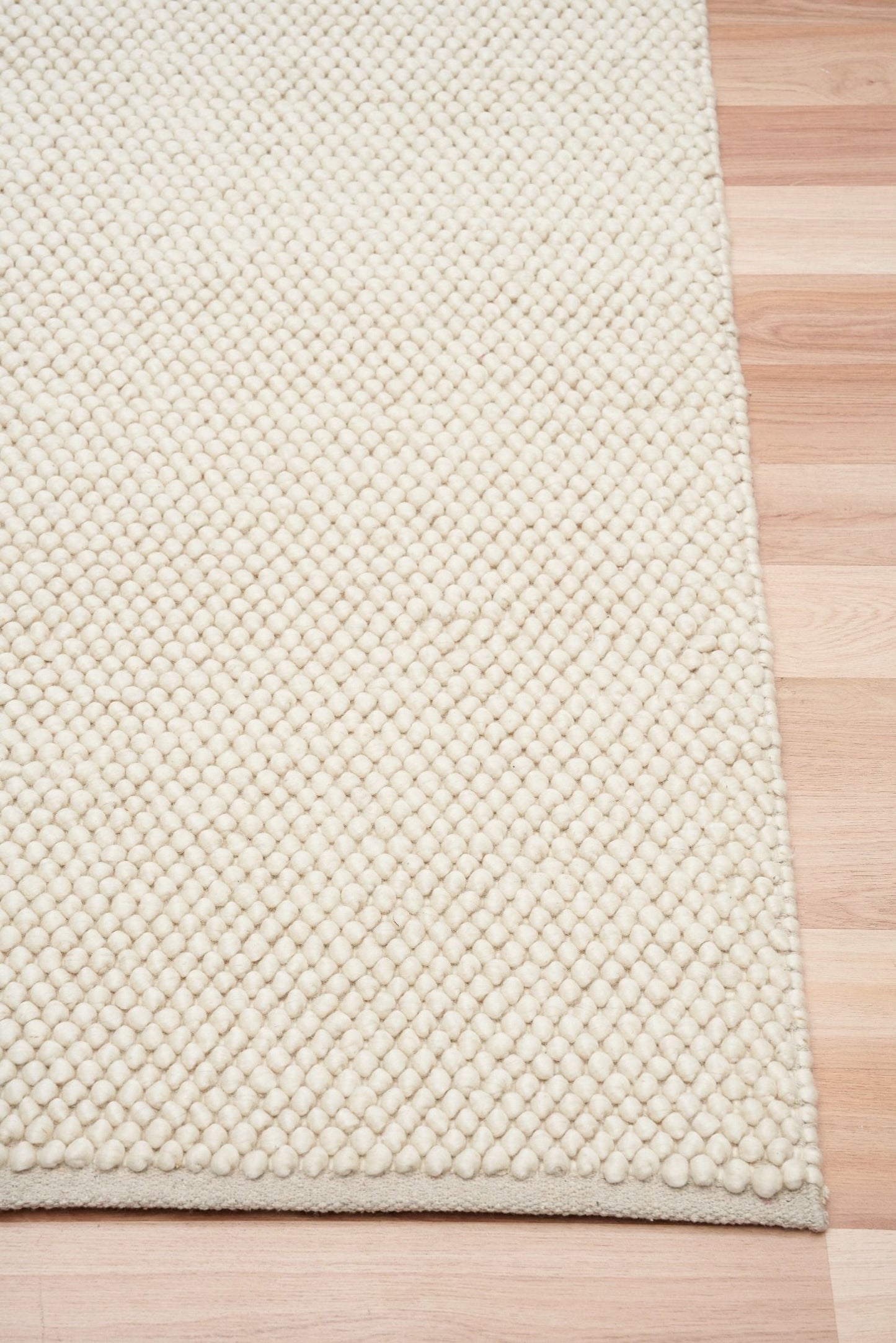 Rusta Cream hand-woven wool rug featuring a looped pile textured design in soft neutral cream tones, ideal for modern and contemporary interiors. Sizes 155 X 225, 200 X 290, 240 X 320 and 300 X 400. Corner.