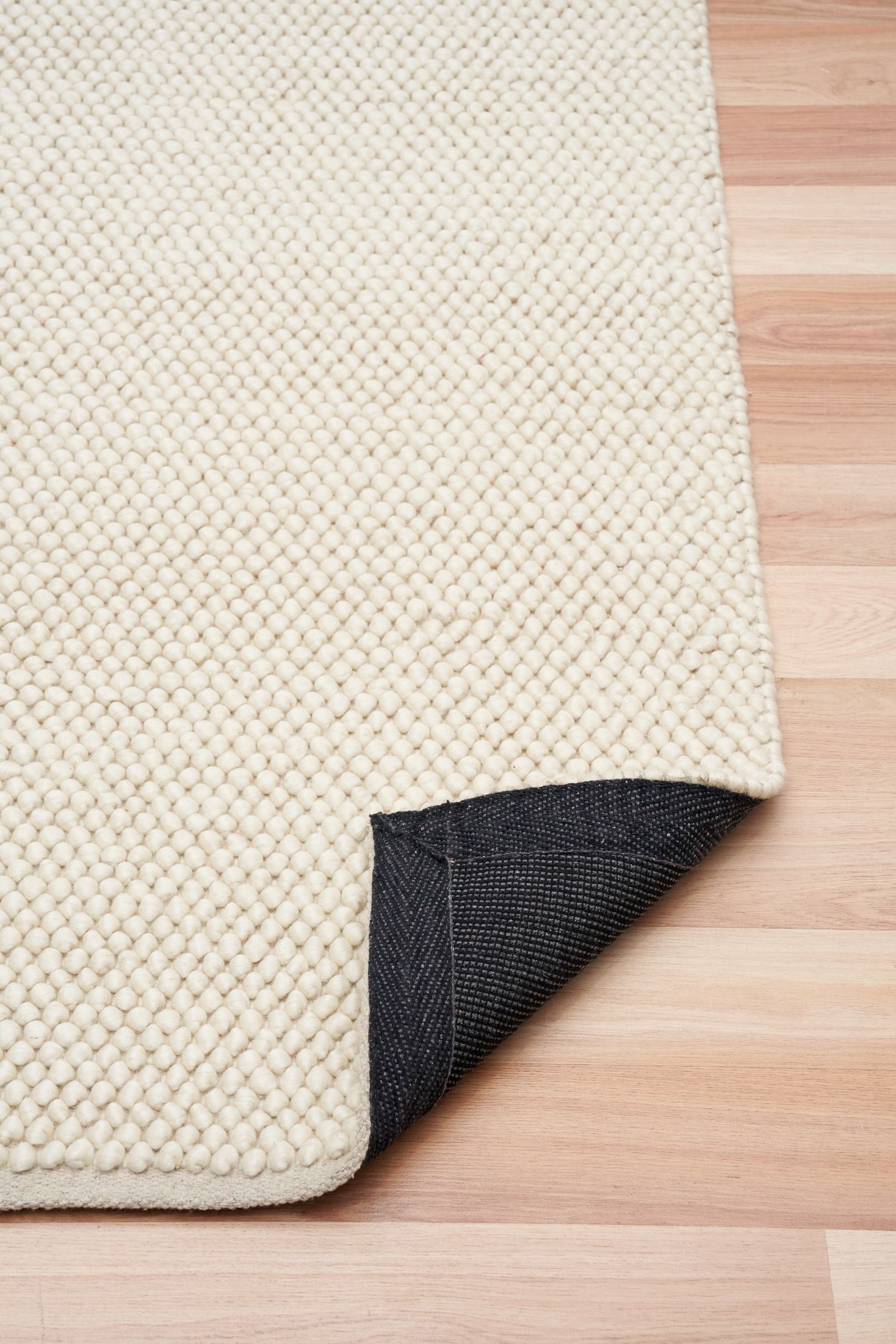 Rusta Cream hand-woven wool rug featuring a looped pile textured design in soft neutral cream tones, ideal for modern and contemporary interiors. Sizes 155 X 225, 200 X 290, 240 X 320 and 300 X 400. Fold.