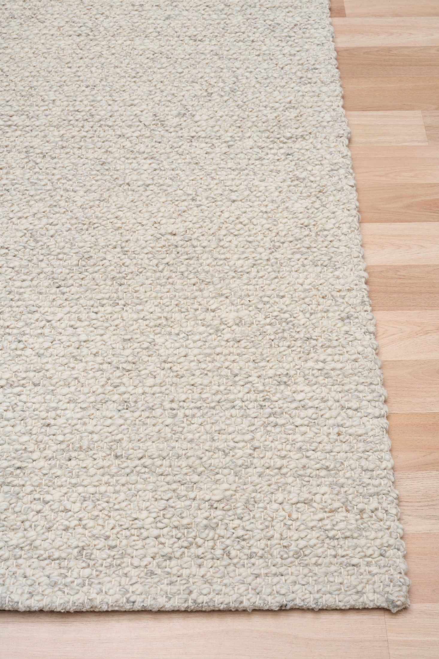 Sahara Grey Rug – hand woven 100% wool rug in soft neutral tones with a textured finish, available in three sizes, styled for modern and coastal homes. Corner.