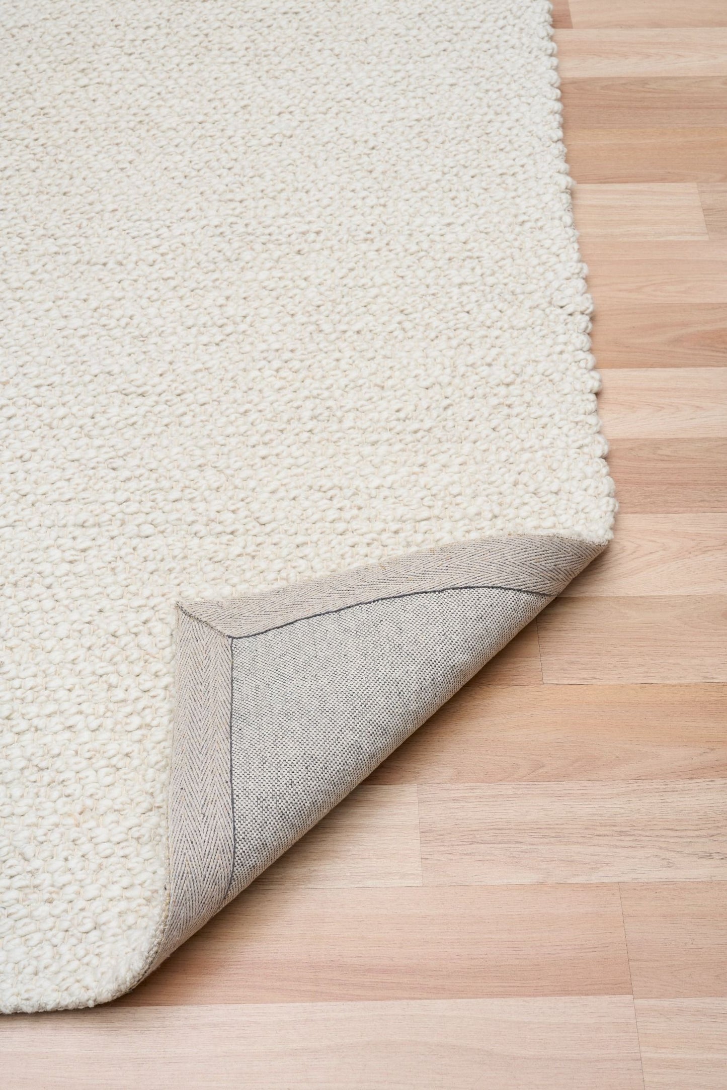 Sahara Ivory Rug – hand woven 100% wool rug in soft neutral tones with a textured finish, available in three sizes, styled for modern and coastal homes. Fold.