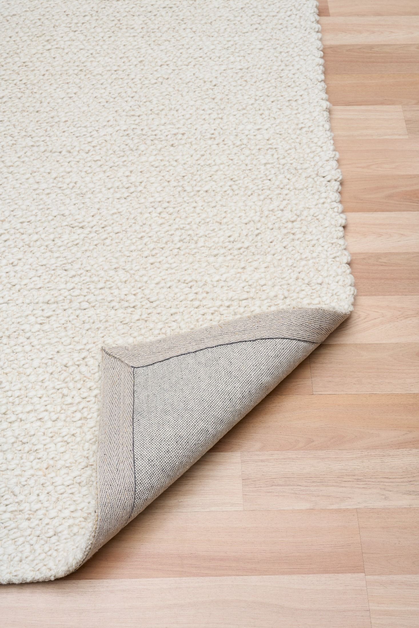Sahara Ivory Rug – hand woven 100% wool rug in soft neutral tones with a textured finish, available in three sizes, styled for modern and coastal homes. Fold.