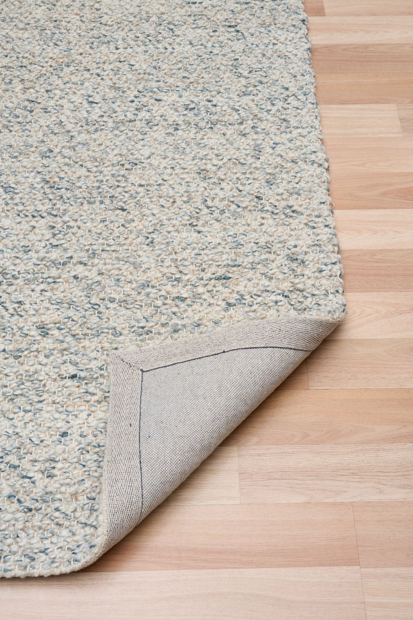 Sahara Teal Rug – hand woven 100% wool rug in soft neutral tones with a textured finish, available in three sizes, styled for modern and coastal homes. Fold.
