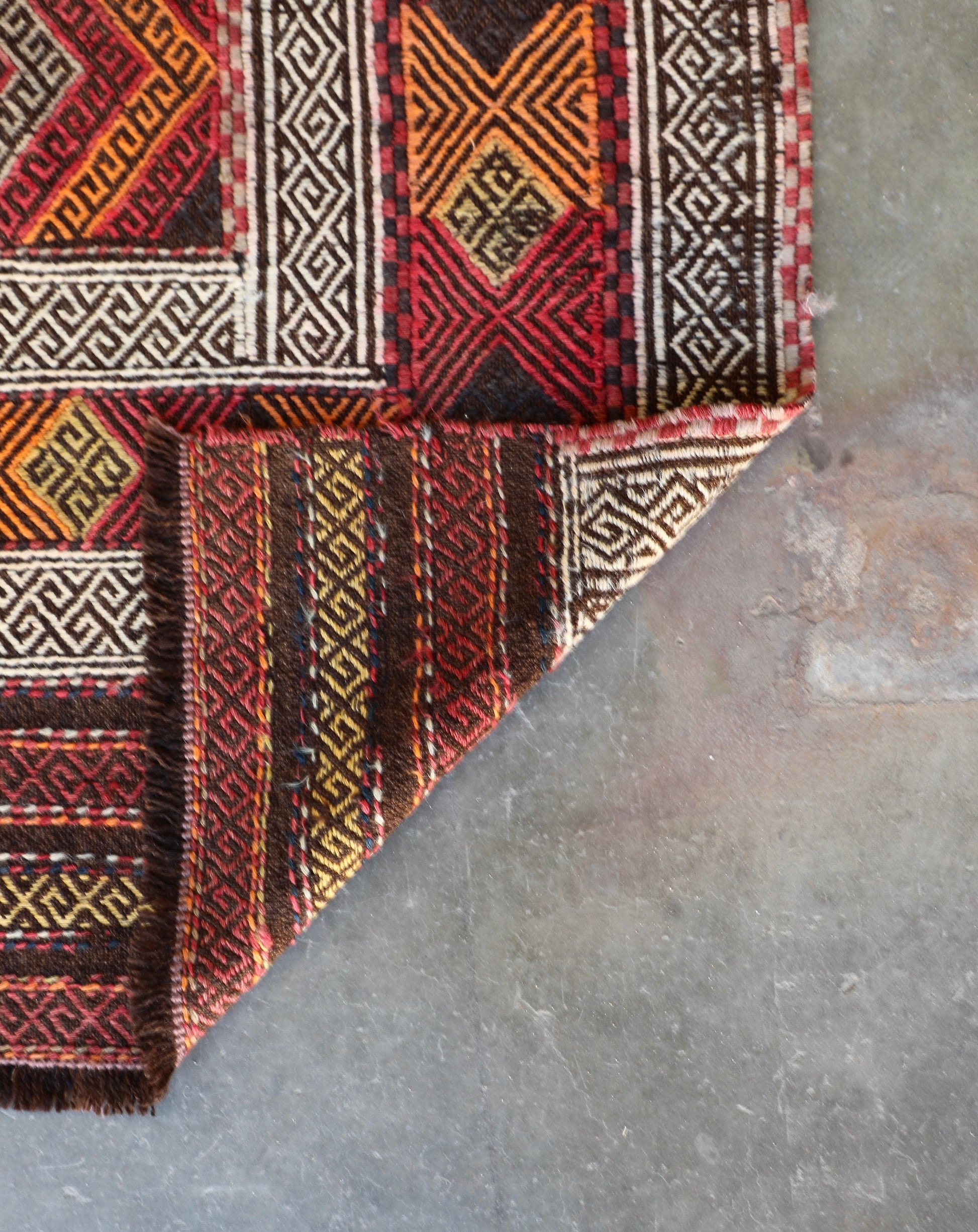The Afghan Hand Woven Wool Suzani Kilim - 151 X 286. Hand woven by skilled afghan weavers, and featuring traditional bold geometric designs. Colours, oranges, reds, browns and creams. Measures 151 wide X 286 long. Fold.