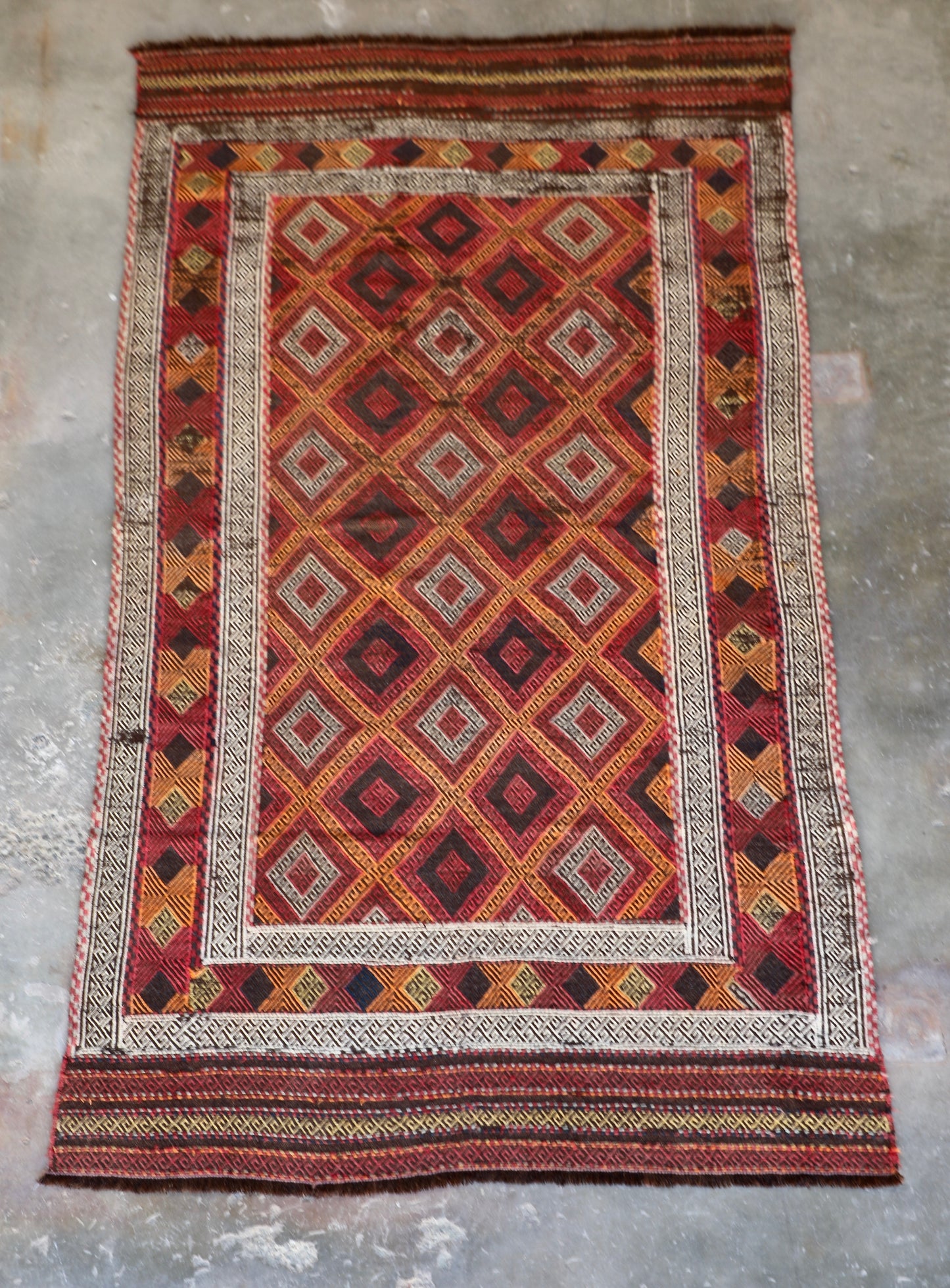 The Afghan Hand Woven Wool Suzani Kilim - 151 X 286. Hand woven by skilled afghan weavers, and featuring traditional bold geometric designs. Colours, oranges, reds, browns and creams. Measures 151 wide X 286 long. Front.