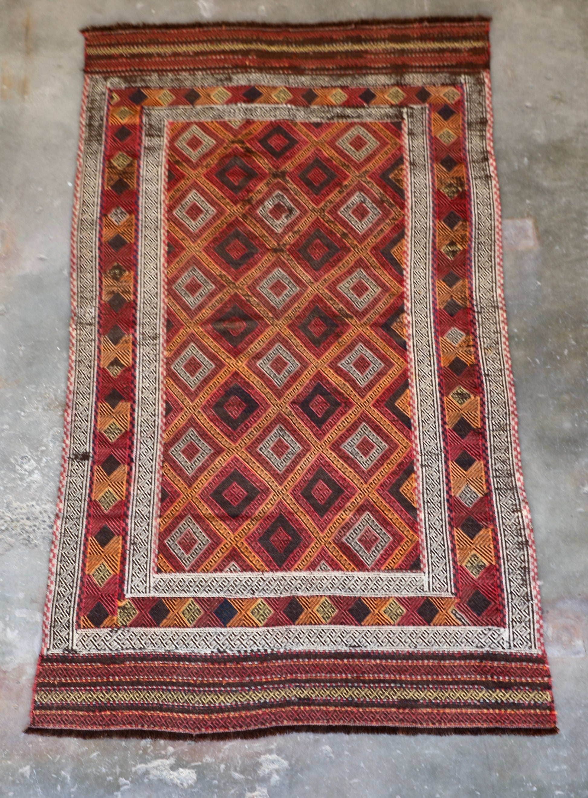 The Afghan Hand Woven Wool Suzani Kilim - 151 X 286. Hand woven by skilled afghan weavers, and featuring traditional bold geometric designs. Colours, oranges, reds, browns and creams. Measures 151 wide X 286 long. Front.
