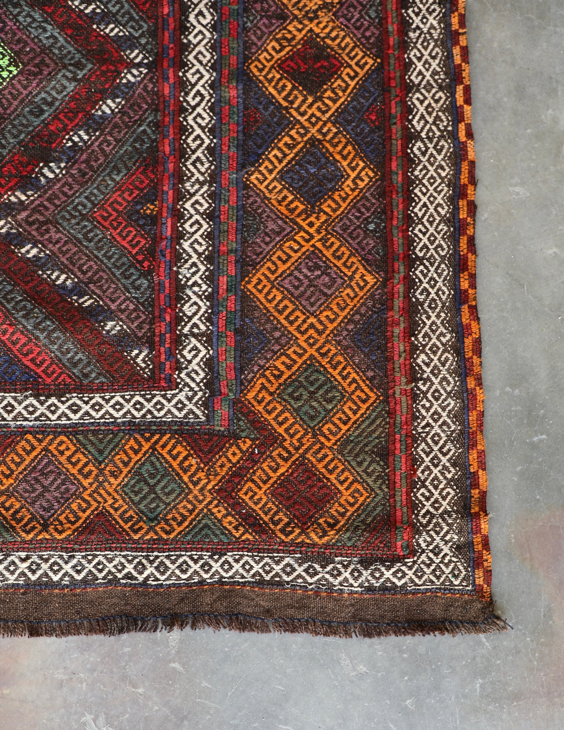 The Afghan Hand Woven Wool Suzani Kilim - 155 X 251. Features traditional geometric designs, hand crafted by Afghan artisan weavers. Colours, dark browns, oranges, blues and creams. Measures 155 wide X 251 long. Corner.