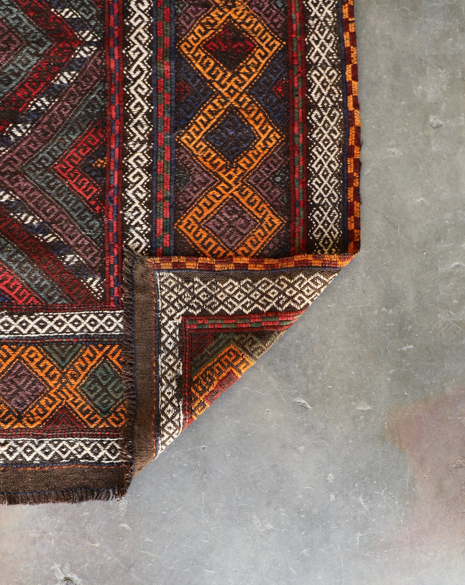 The Afghan Hand Woven Wool Suzani Kilim - 155 X 251. Features traditional geometric designs, hand crafted by Afghan artisan weavers. Colours, dark browns, oranges, blues and creams. Measures 155 wide X 251 long. Fold.