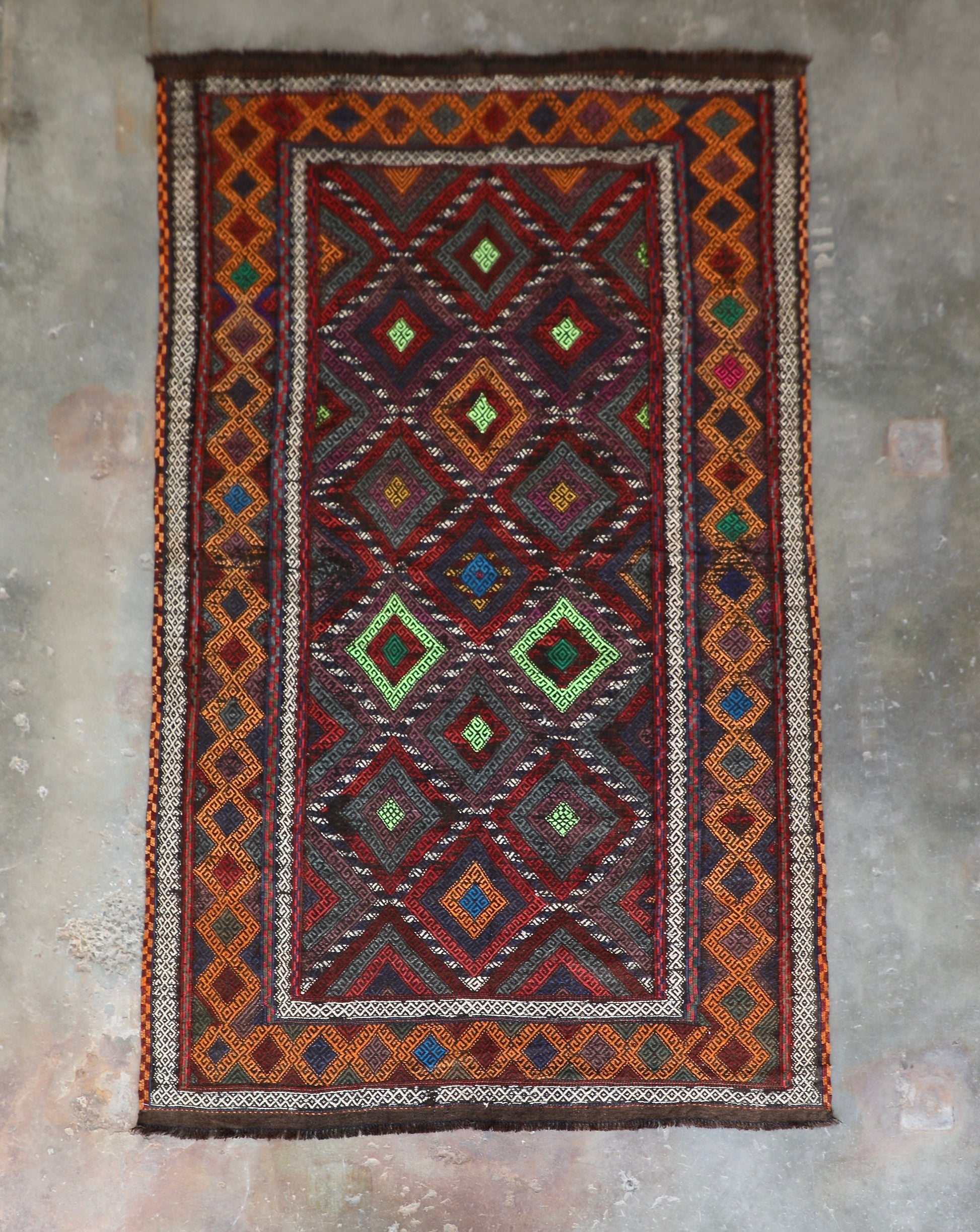 The Afghan Hand Woven Wool Suzani Kilim - 155 X 251. Features traditional geometric designs, hand crafted by Afghan artisan weavers. Colours, dark browns, oranges, blues and creams. Measures 155 wide X 251 long. Front.