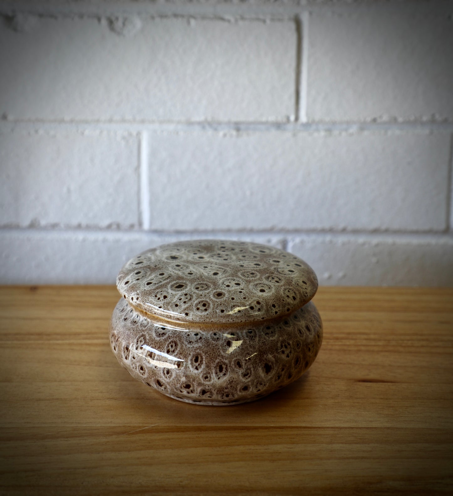 The Terra Ceramic Candle Jar, features a main dish for the candle and a lid to cover when not in use.  Colours rustic grey with black specs. Measures 12.5 Diameter X 7 Height. Closed.