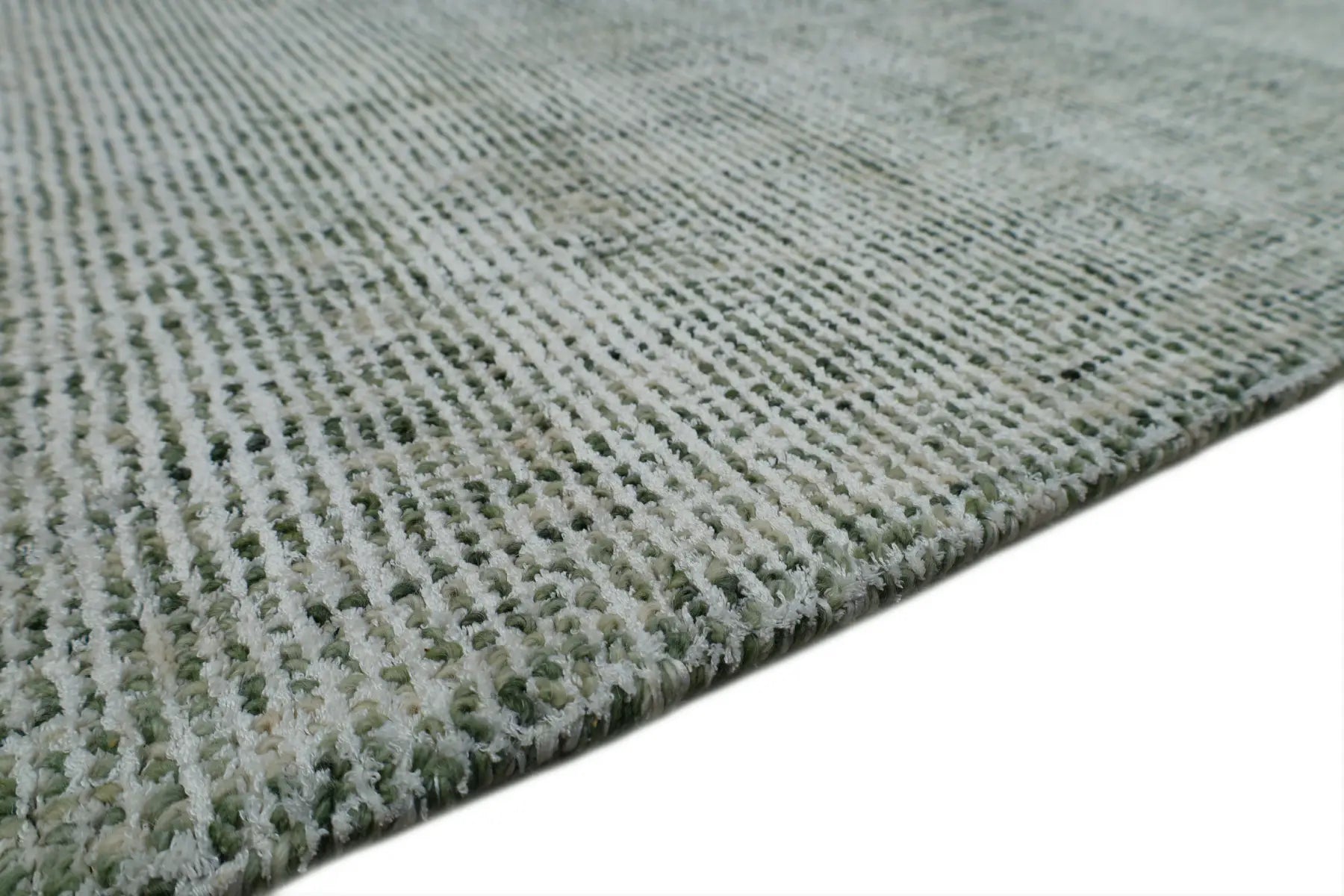 Toro Green is a hand-loomed, hand-knotted rug with a contemporary multi-fleck design. Wool and silky viscose are blended to create a soft feel with its 10-12mm pile height. Colour emerald green with white accents. Sizes 160 X 230, 200 X 290, 240 X 340 and 300 X 400. Side.