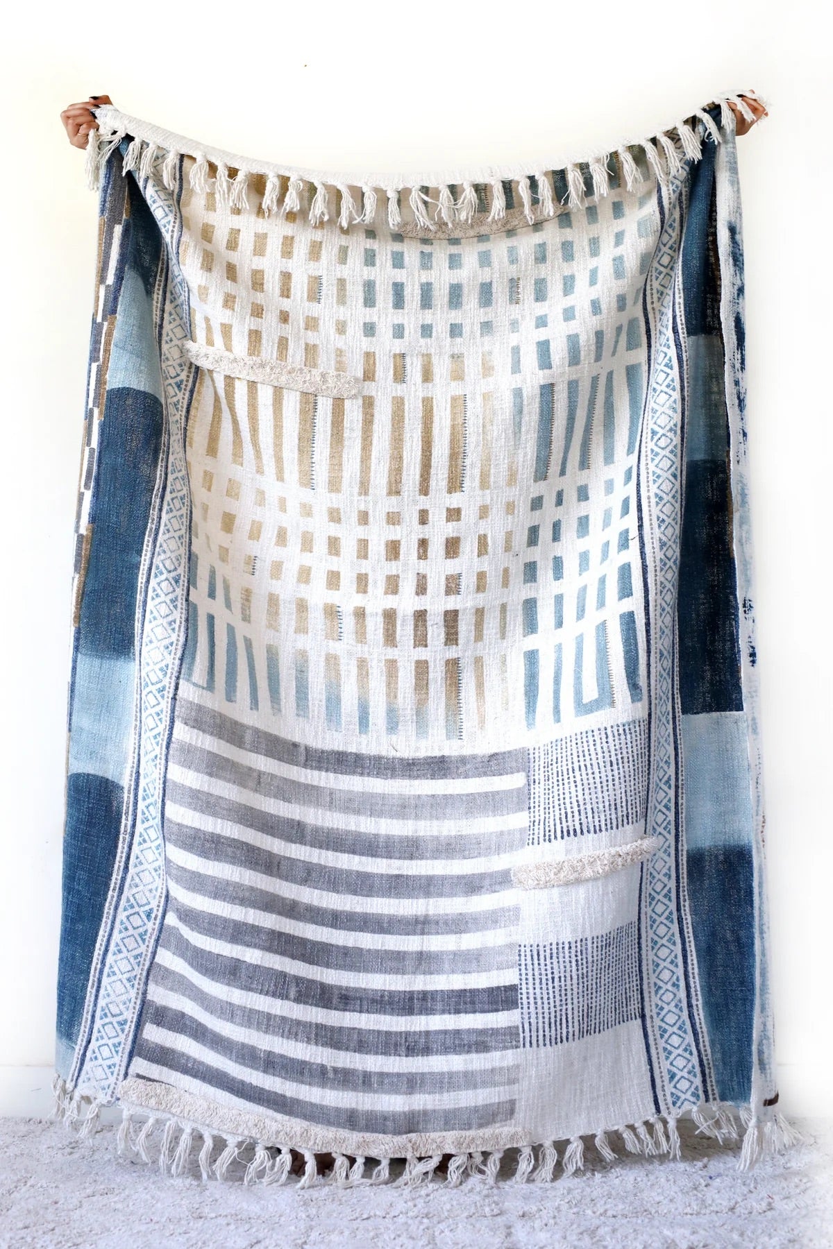 The Urbanic handcrafted throw blanket, adorned with a block print and playful tassels. Crafted from cotton slub from skilled artisans in India. It features a smooth textured feel. Indulge in the latest trend of Geometric Art with stunning shades of blue. Colours, blues, whites, beiges and greys. Size 130 X 170. Front 