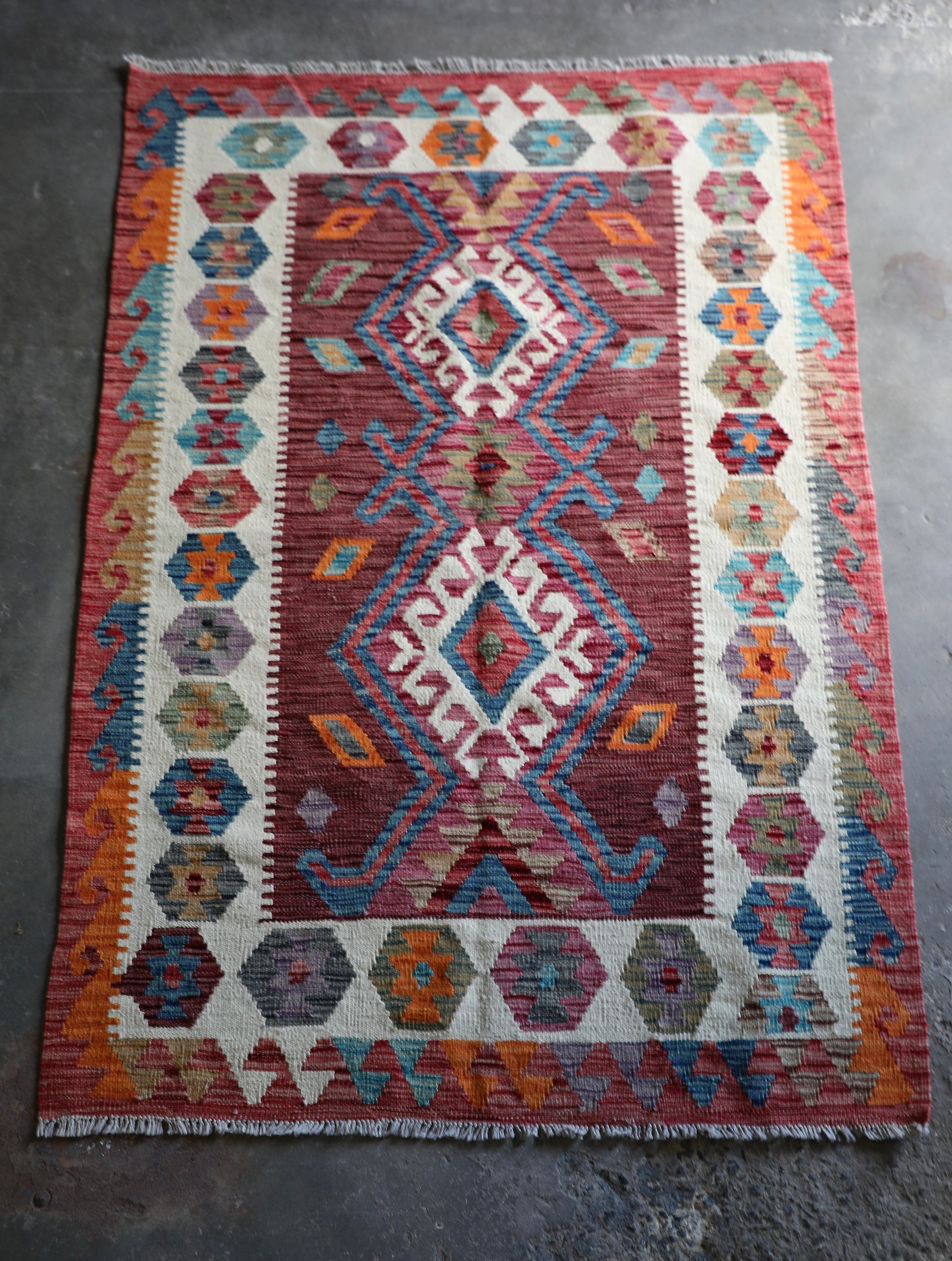 The Afghan Hand Woven Khyber Kilim 122 X 183. Crafted using traditional vegetable dyed wool, and featuring traditional geometric designs. Colours, reds, oranges, browns, creams and teal greens. Size 122 X 183. Front.