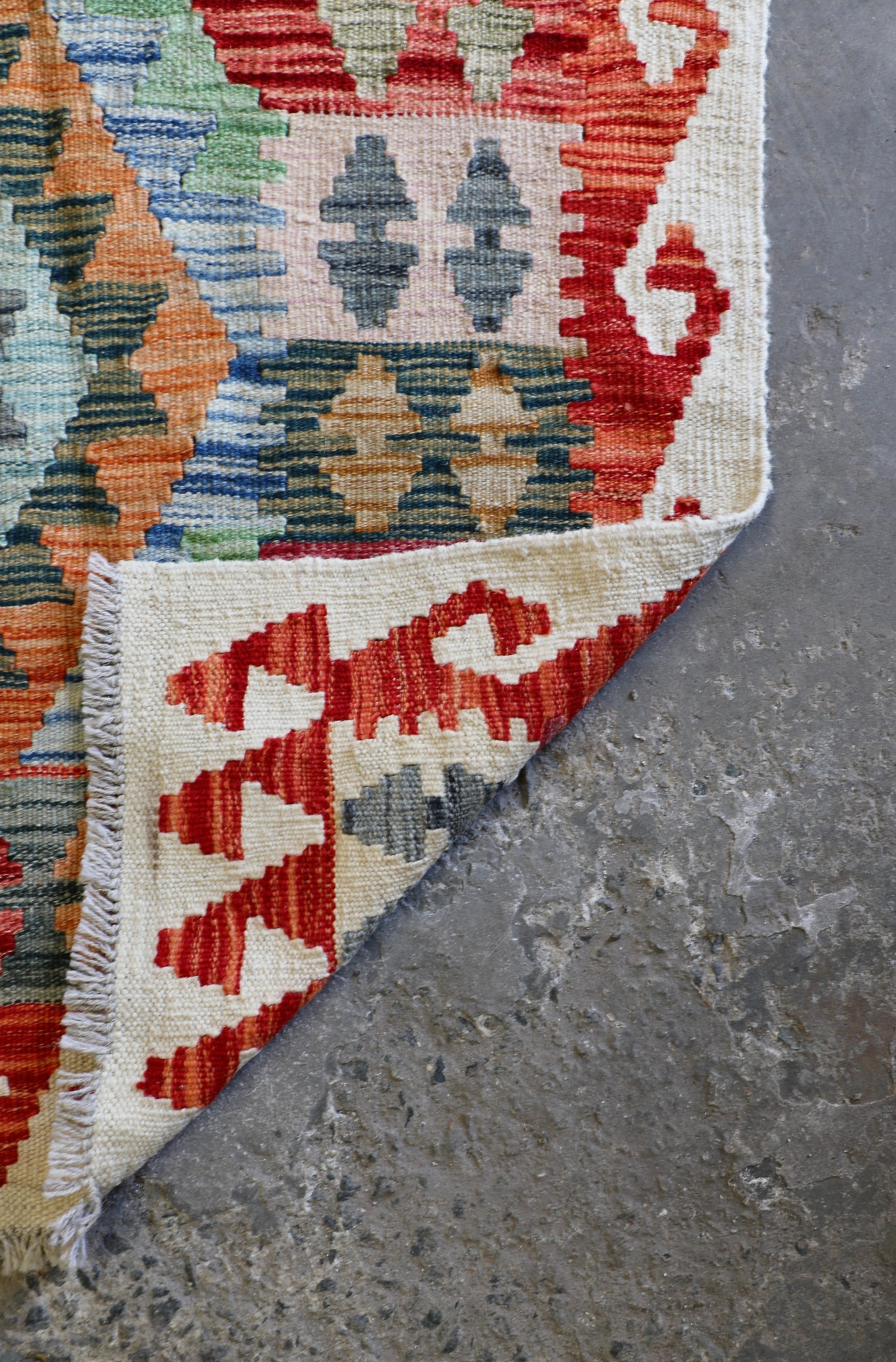 The Afghan Hand Woven Khyber Kilim - 124 X 178. Crafted using traditional vegetable dyed wool, and featuring traditional geometric designs. Colours, creams, oranges, greens and blues. Size 124 X 178. Fold.