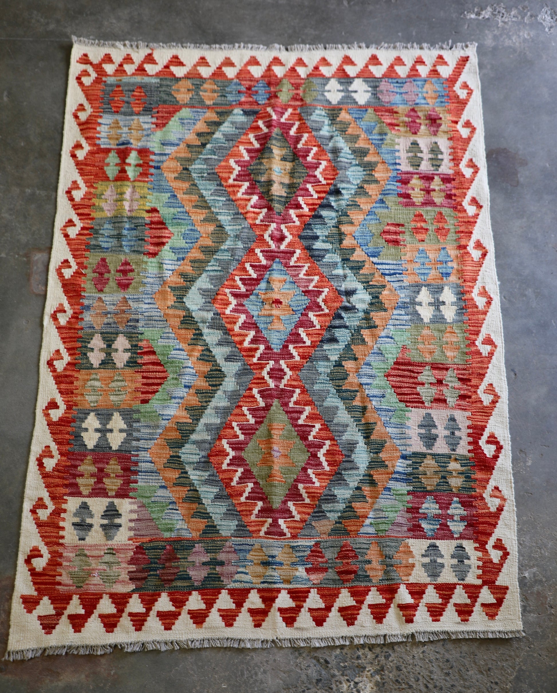 The Afghan Hand Woven Khyber Kilim - 124 X 178. Crafted using traditional vegetable dyed wool, and featuring traditional geometric designs. Colours, creams, oranges, greens and blues. Size 124 X 178. Front.