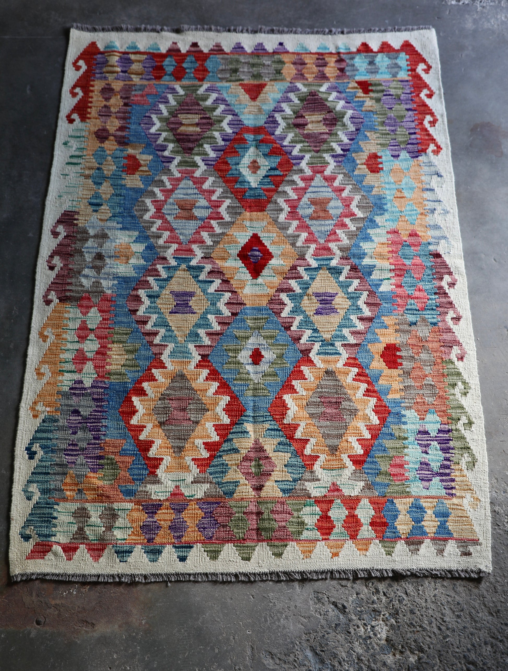 The Afghan Khyber Kilim - 126 X 178.  Crafted using traditional vegetable dyed wool, and featuring traditional geometric designs. Colours, Beige, blue, red, yellow brown. Size 126 X 178. Front.