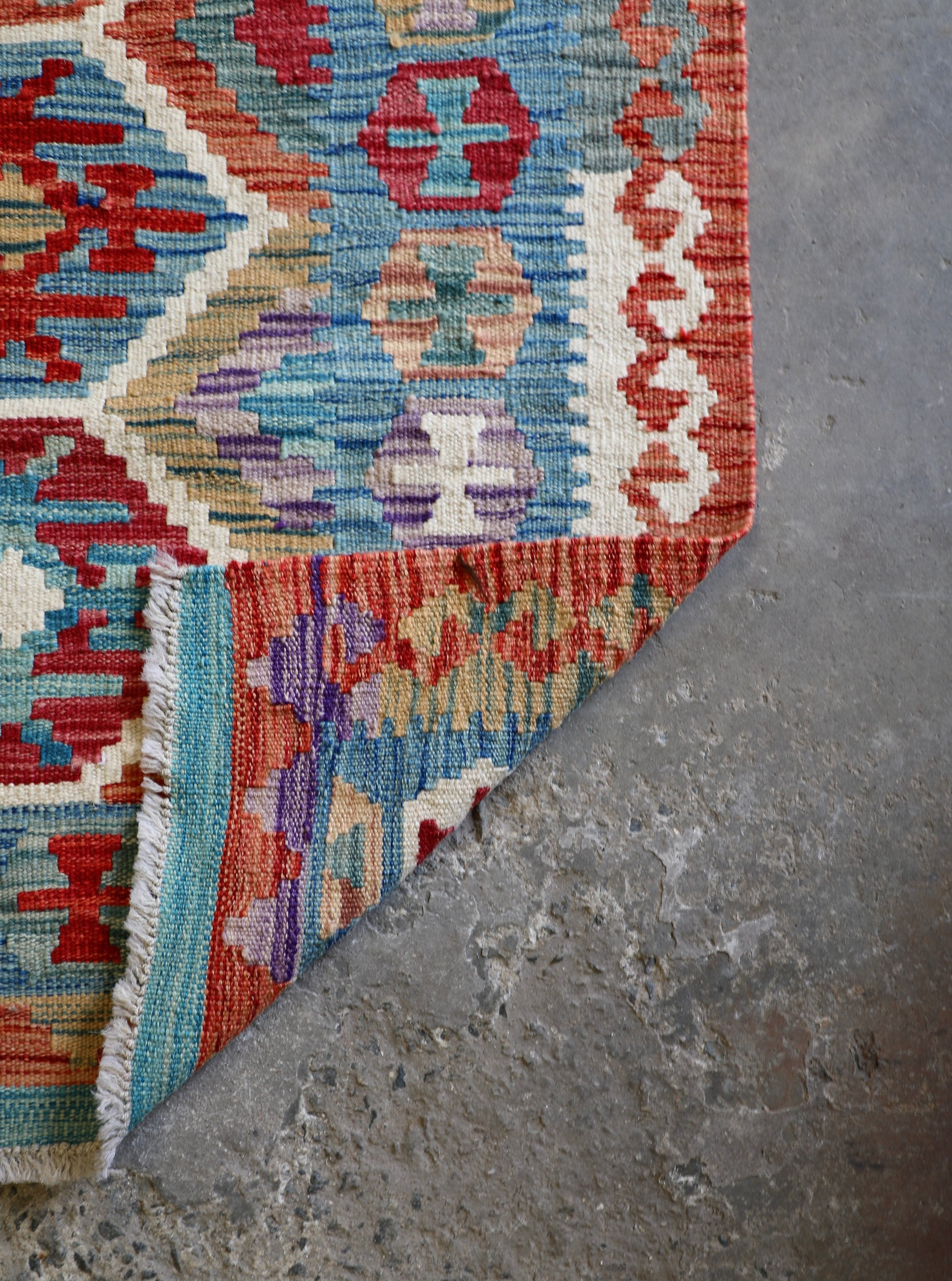 The Afghan Hand Woven Khyber Kilim - 129 X 178.  Crafted using traditional vegetable dyed wool, and featuring traditional geometric designs. Colours, brown, red, blue, cream, teal. Size 129 X 178. Fold.