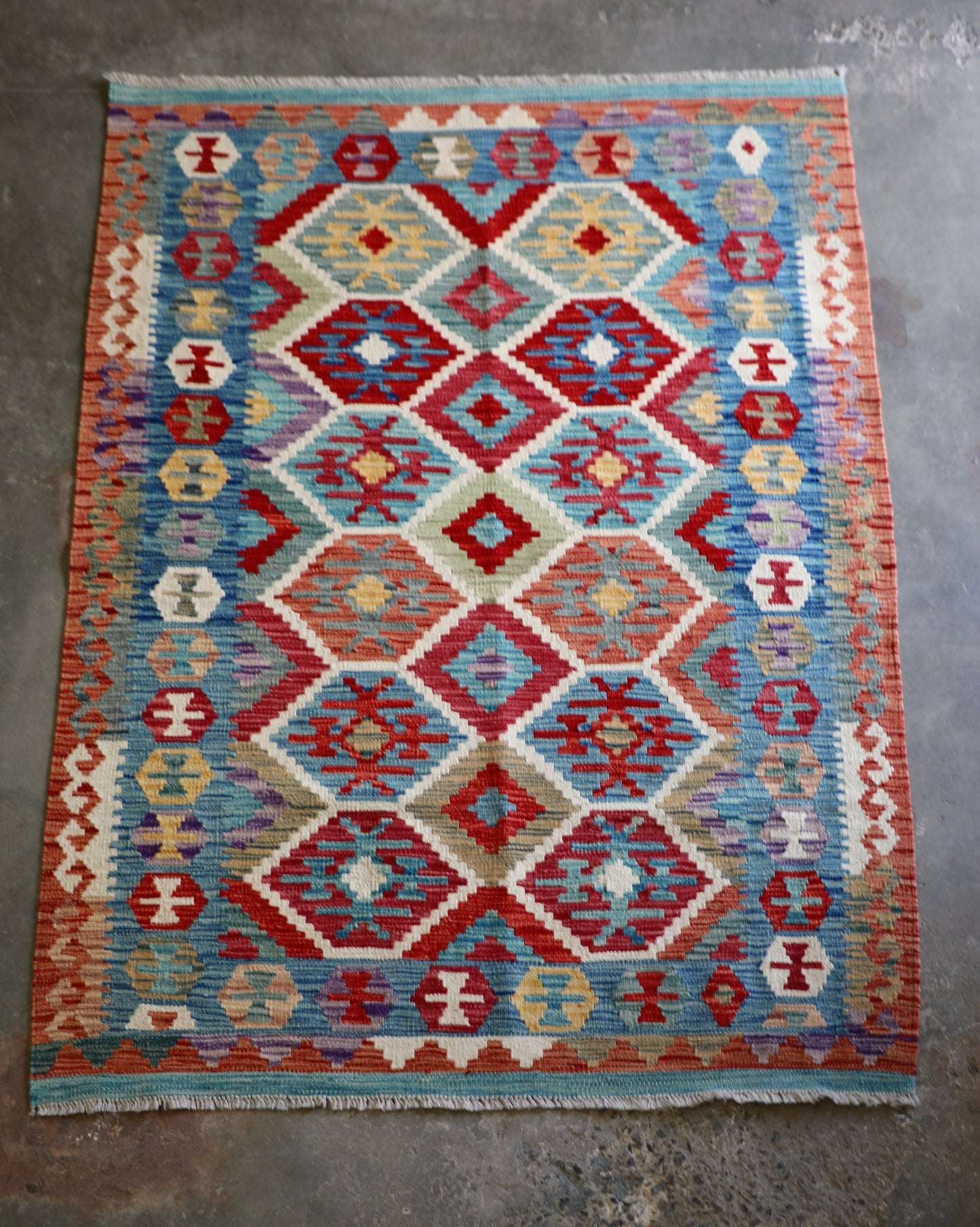 The Afghan Hand Woven Khyber Kilim - 129 X 178.  Crafted using traditional vegetable dyed wool, and featuring traditional geometric designs. Colours, brown, red, blue, cream, teal. Size 129 X 178. Front.